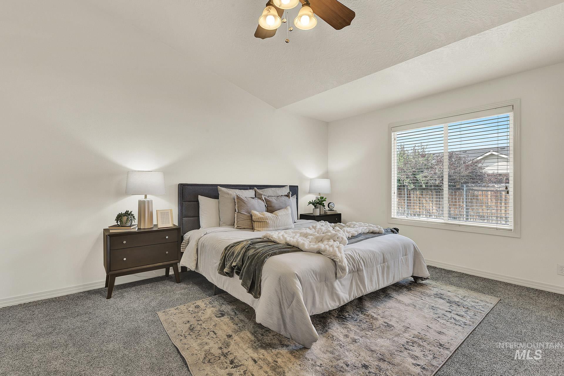 Newly carpeted roomy master bedroom featuring vaulted ceiling, with plenty of natural light, an ensuite bathroom, and ceiling fan. Split floor plan for the bedrooms.