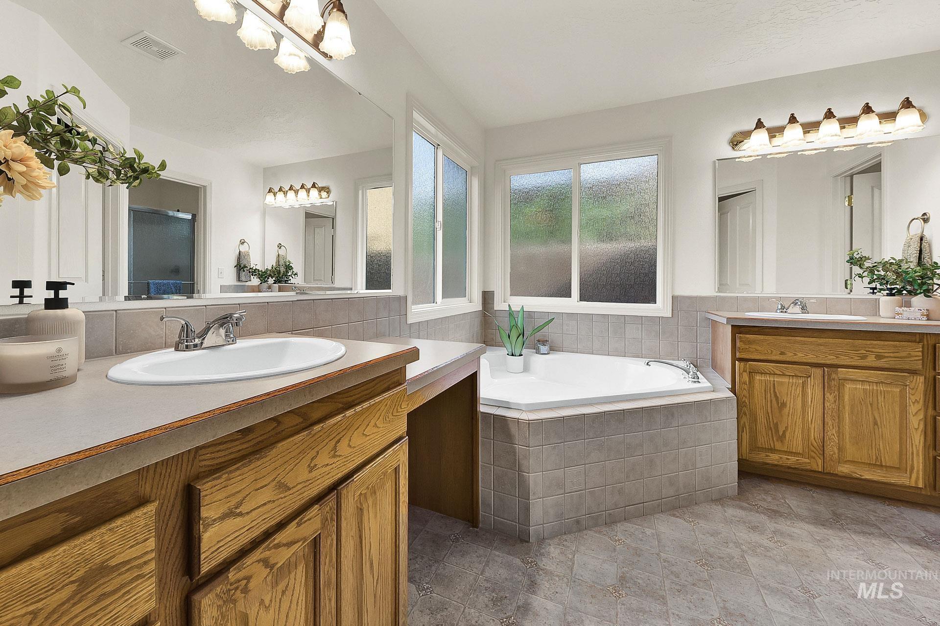 Bathroom with a relaxing corner soaking tub, and separate vanities with plenty of counter space.  Extra large windows with obscure glass to allow natural light in and still have privacy.