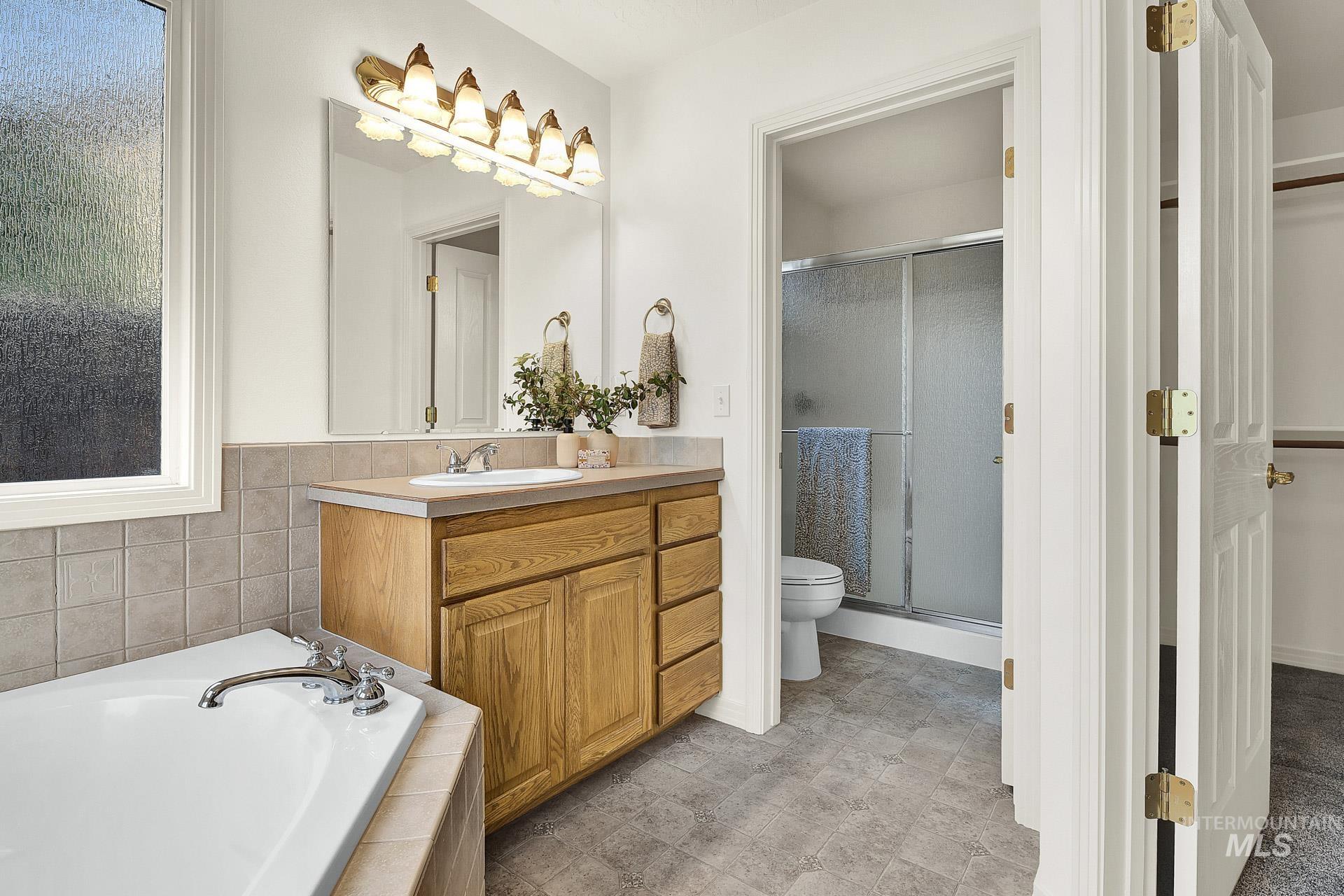 Bathroom with a relaxing corner soaking tub, and separate vanities with plenty of counter space.  Extra large windows with obscure glass to allow natural light in and still have privacy.