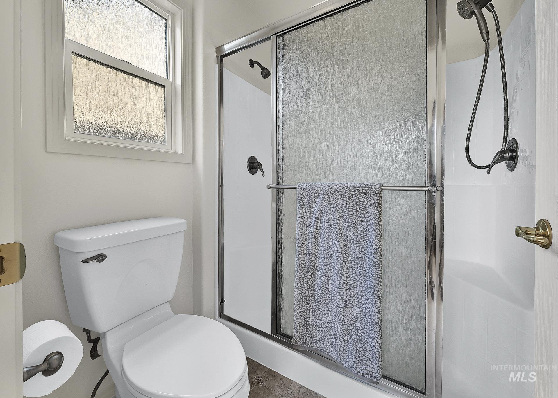Full bathroom featuring a private shower stall and toilet