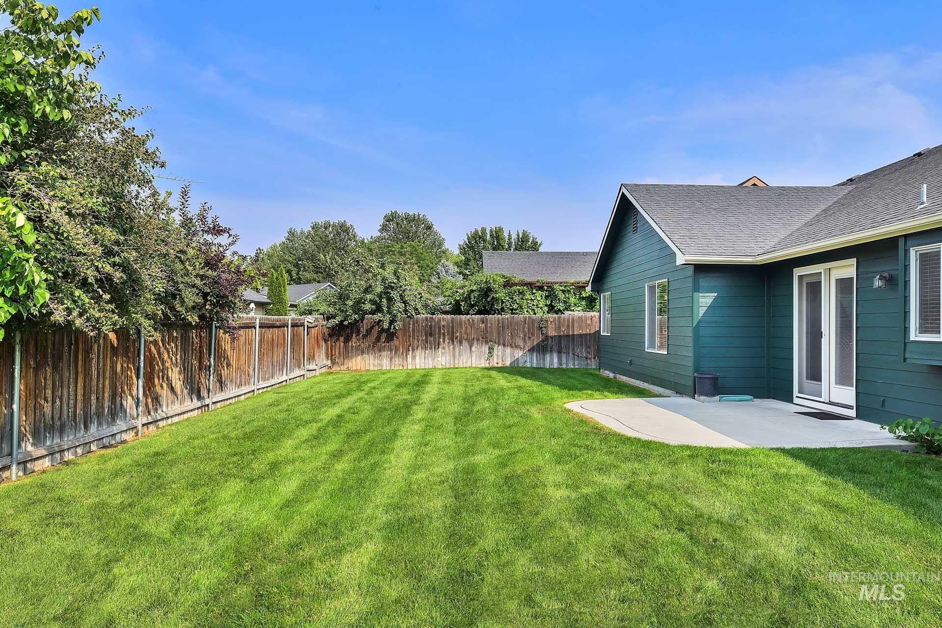 Back of property featuring a patio area, room to set up a BBQ and enjoy this lush green backyard with automatic sprinklers and pressurized irrigation.