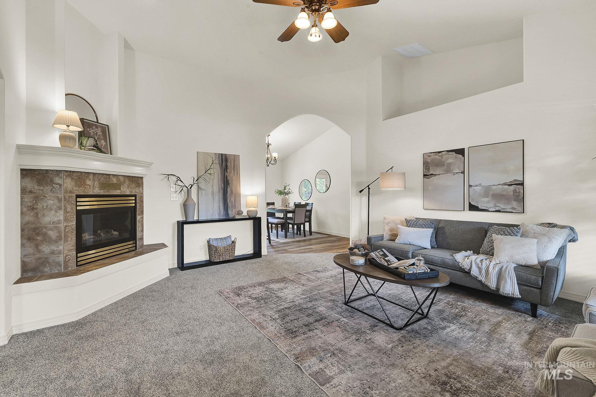 Open Concept! Newly Carpeted and just painted interior living room with an arched doorway, a tile fireplace, high vaulted ceiling, and ceiling fan
