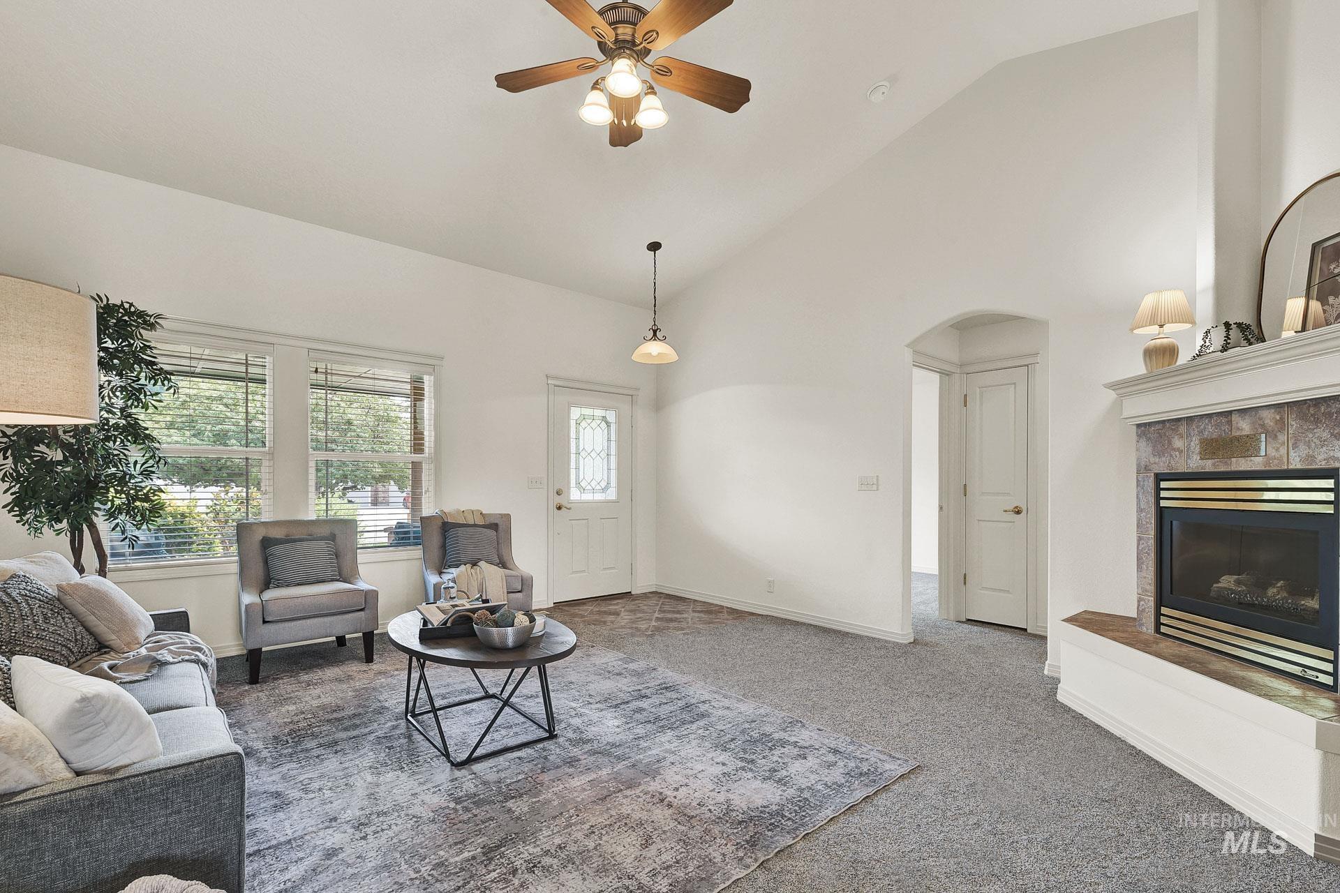Open Concept! Newly Carpeted and just painted interior living room with an arched doorway, a tile fireplace, high vaulted ceiling, and ceiling fan