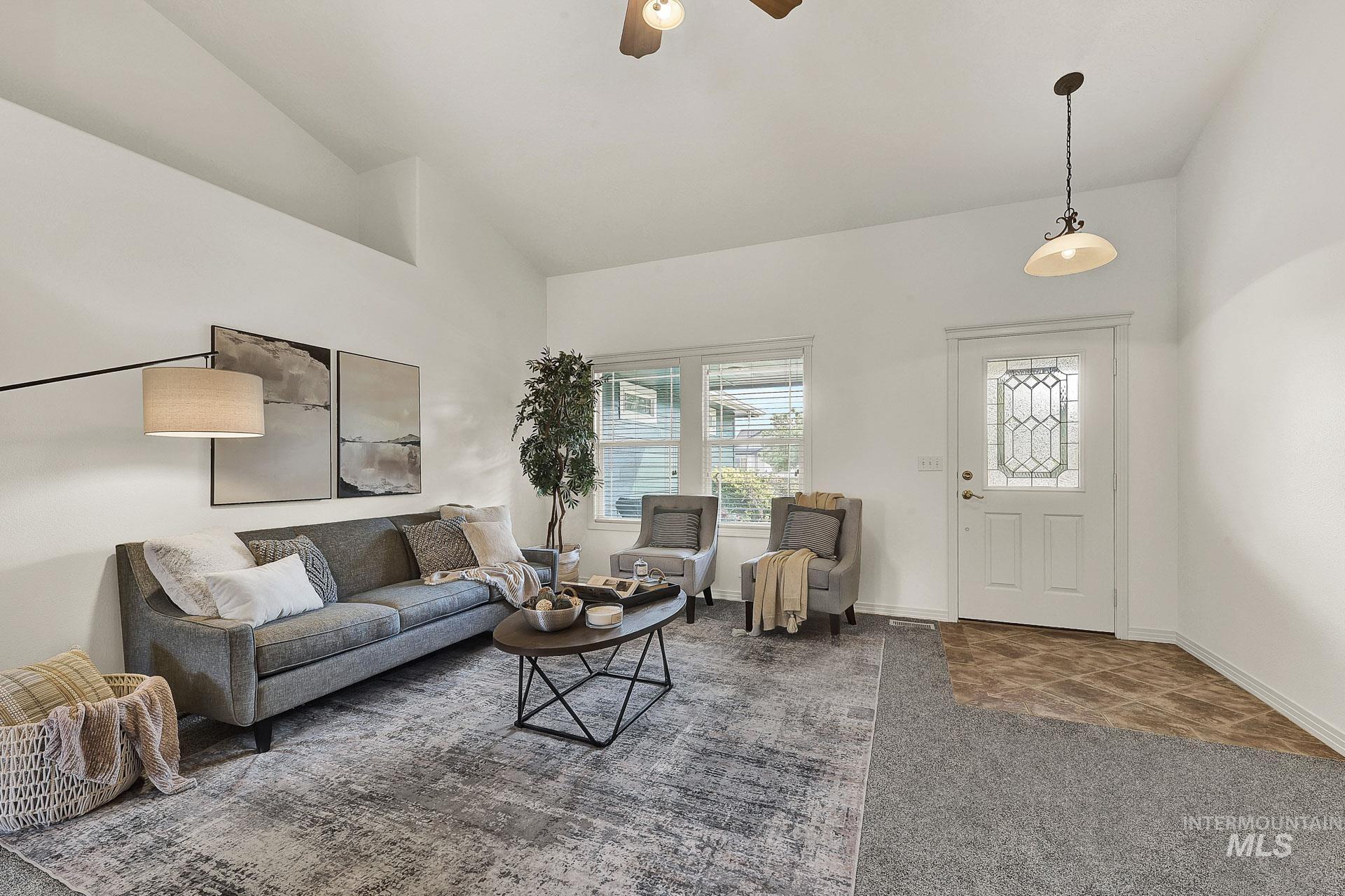 Open concept Living room with new carpet, gas fireplace and ceiling fan, with high vaulted ceiling and built in display or plant shelves