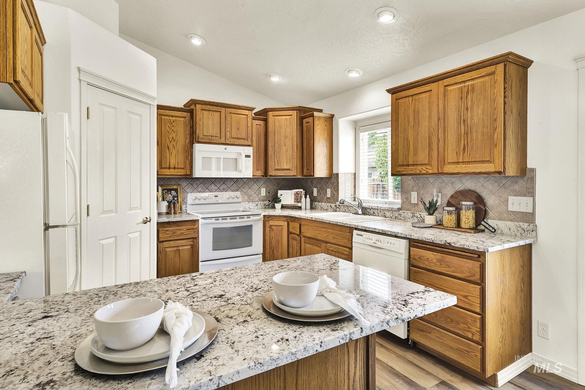 Kitchen with solid wood cabinetry, extra roomy pantry, bisque appliances, newly installed beautiful granite counters, vaulted ceiling and new LVP flooring.