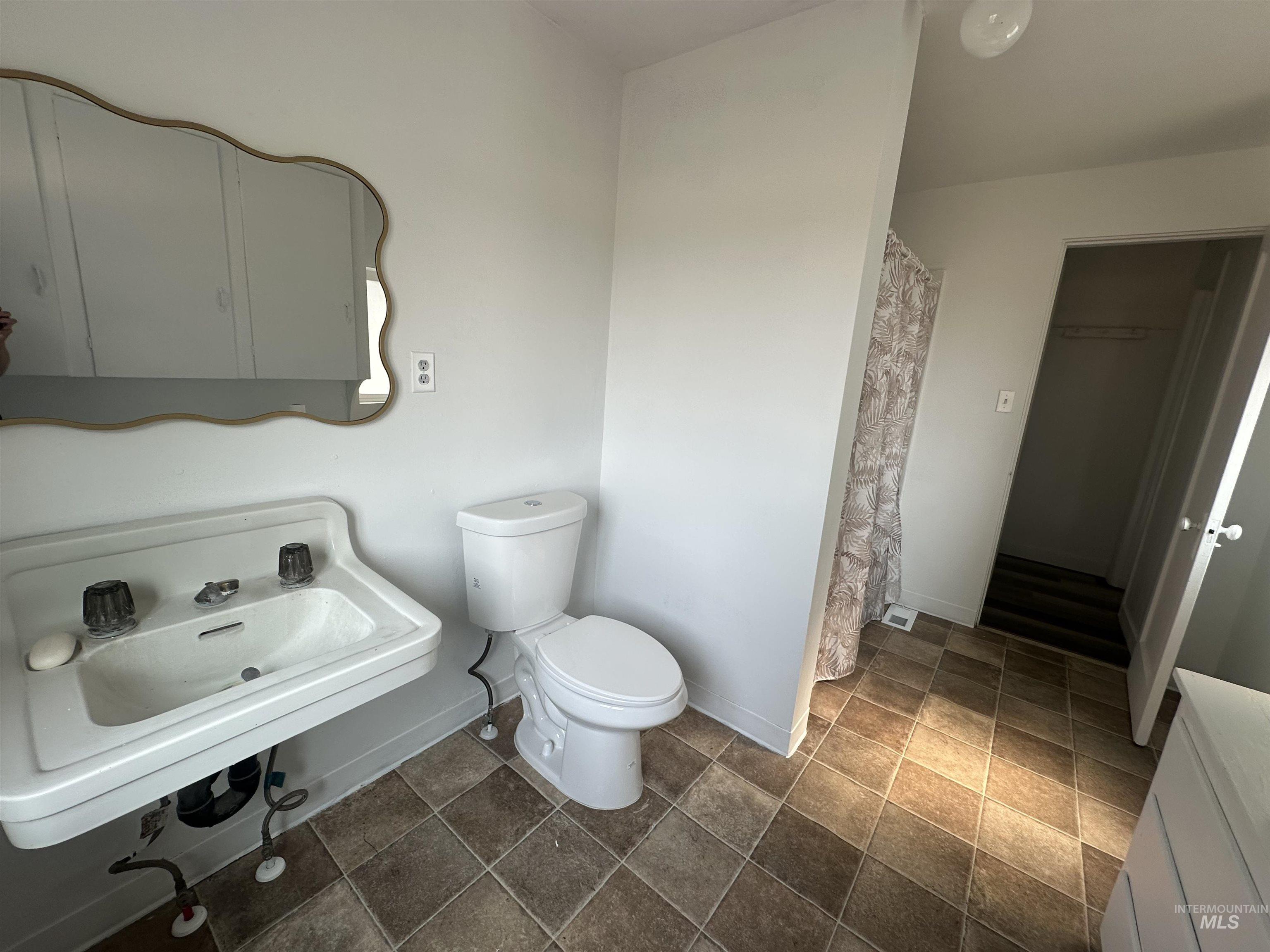 Full bathroom with a shower with curtain, a closet, and dark stone finish floors