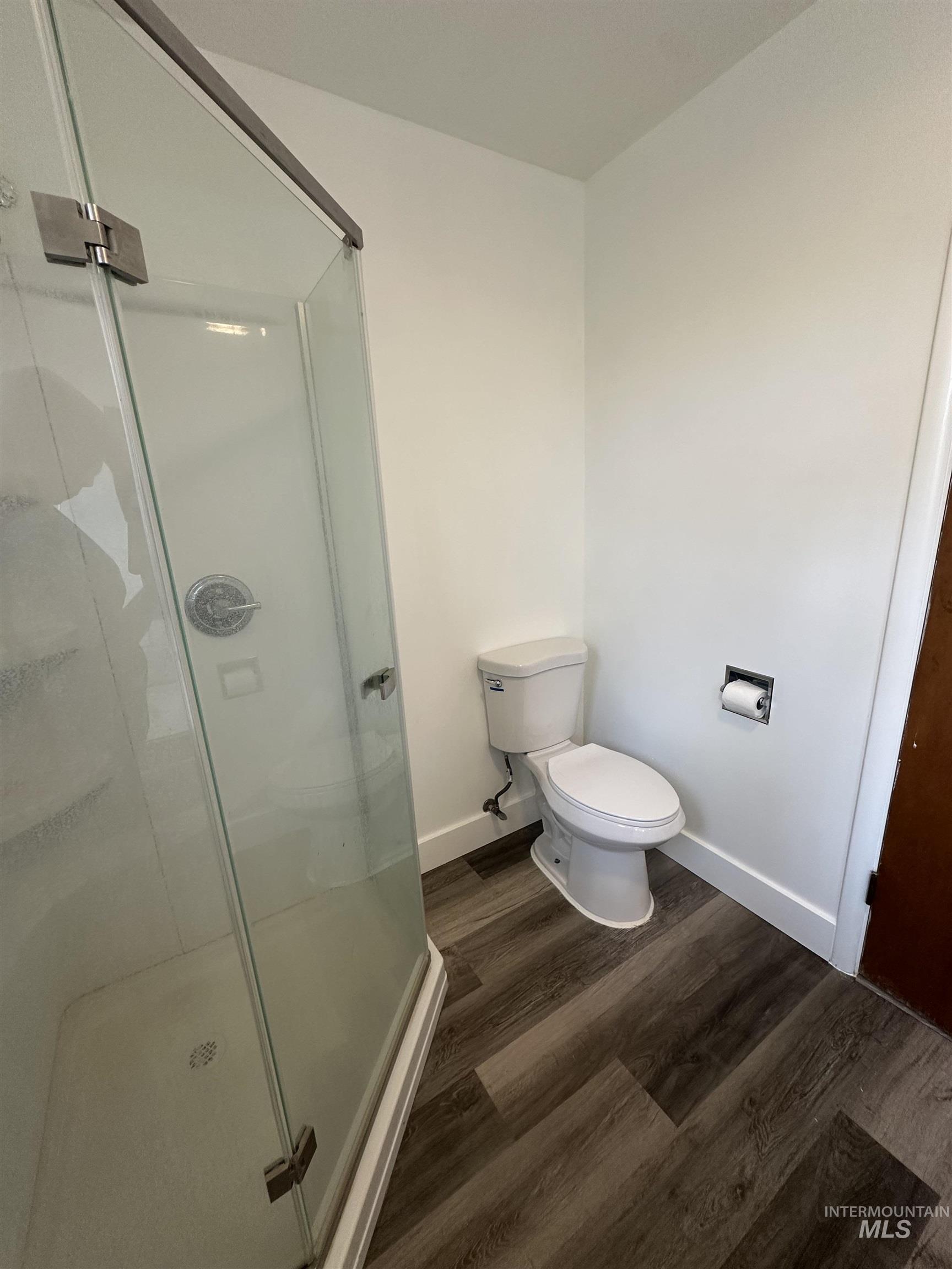 Bathroom with a stall shower and dark wood-type flooring