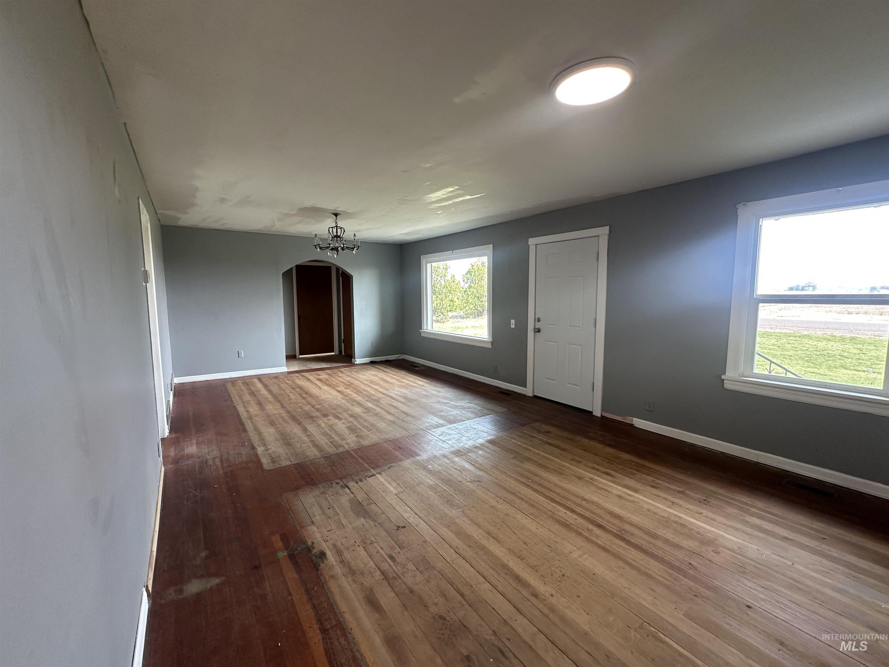 Unfurnished living room featuring arched walkways and dark wood-style flooring