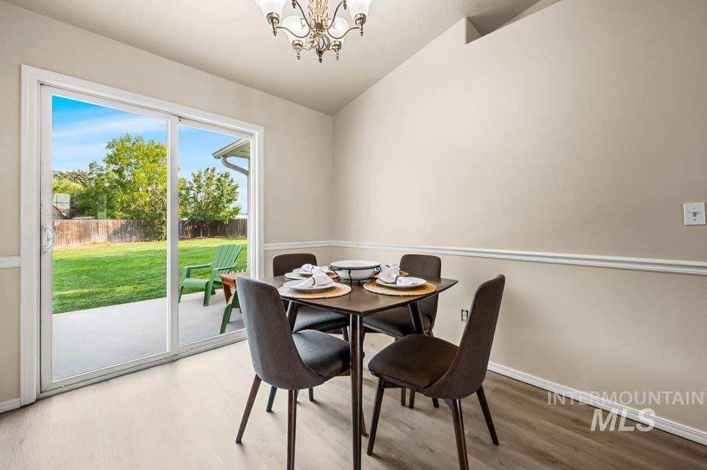 Dining space with wood finished floors, a chandelier, and vaulted ceiling