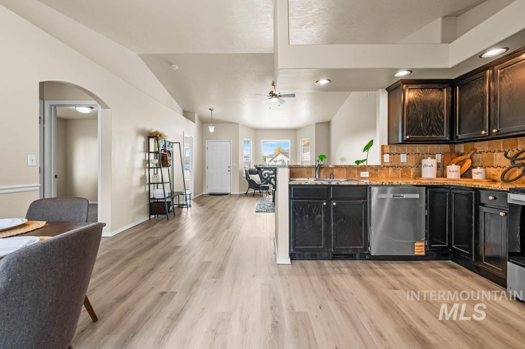 Kitchen featuring tasteful backsplash, light stone countertops, recessed lighting, arched walkways, and appliances with stainless steel finishes