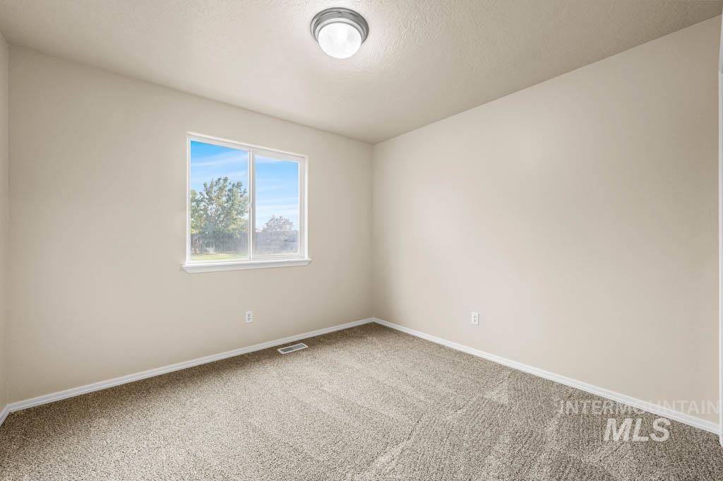 Carpeted empty room featuring baseboards and a textured ceiling