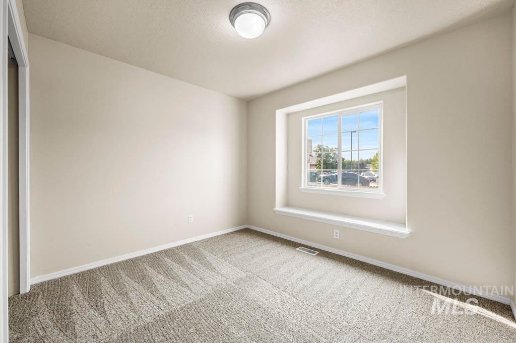 Carpeted empty room featuring baseboards and a textured ceiling
