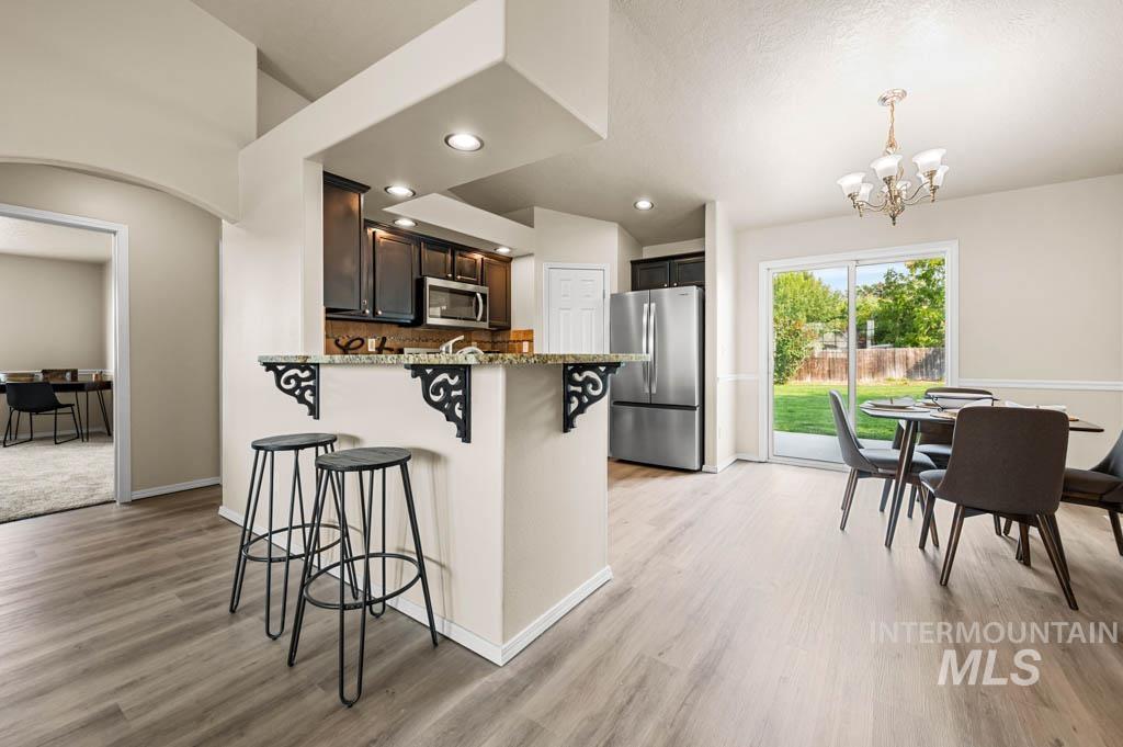 Kitchen with a kitchen breakfast bar, appliances with stainless steel finishes, a peninsula, a chandelier, and recessed lighting