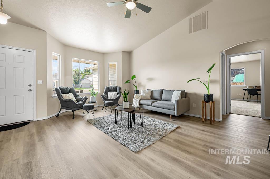 Living room featuring light wood finished floors, ceiling fan, and high vaulted ceiling