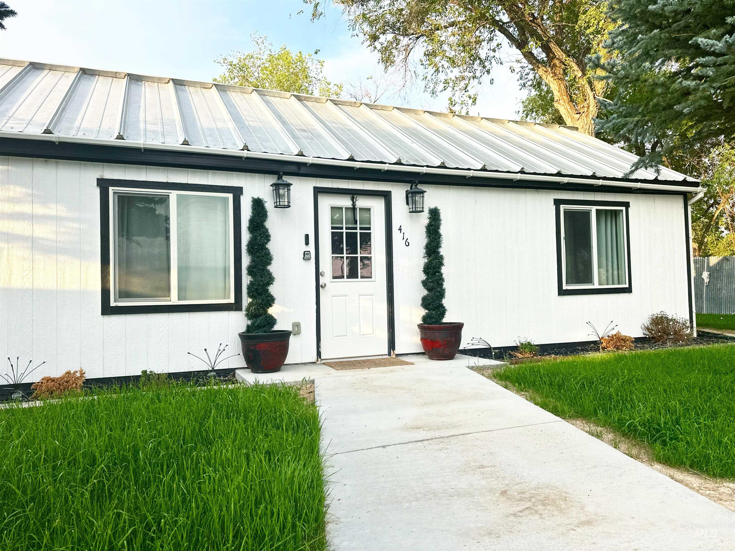 View of exterior entry with a metal roof and a yard