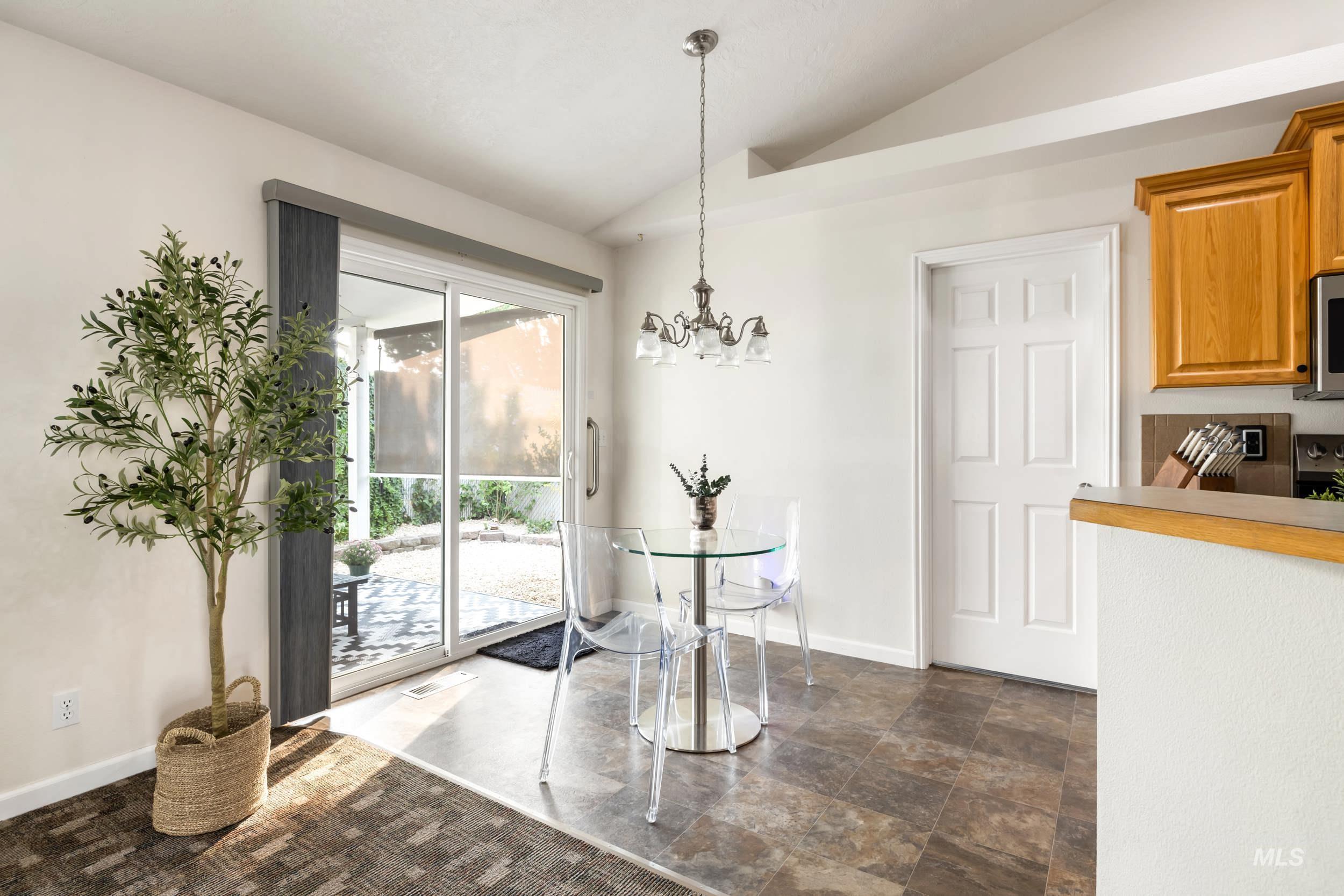 Dining room with lofted ceiling, a chandelier, and dark stone finish flooring