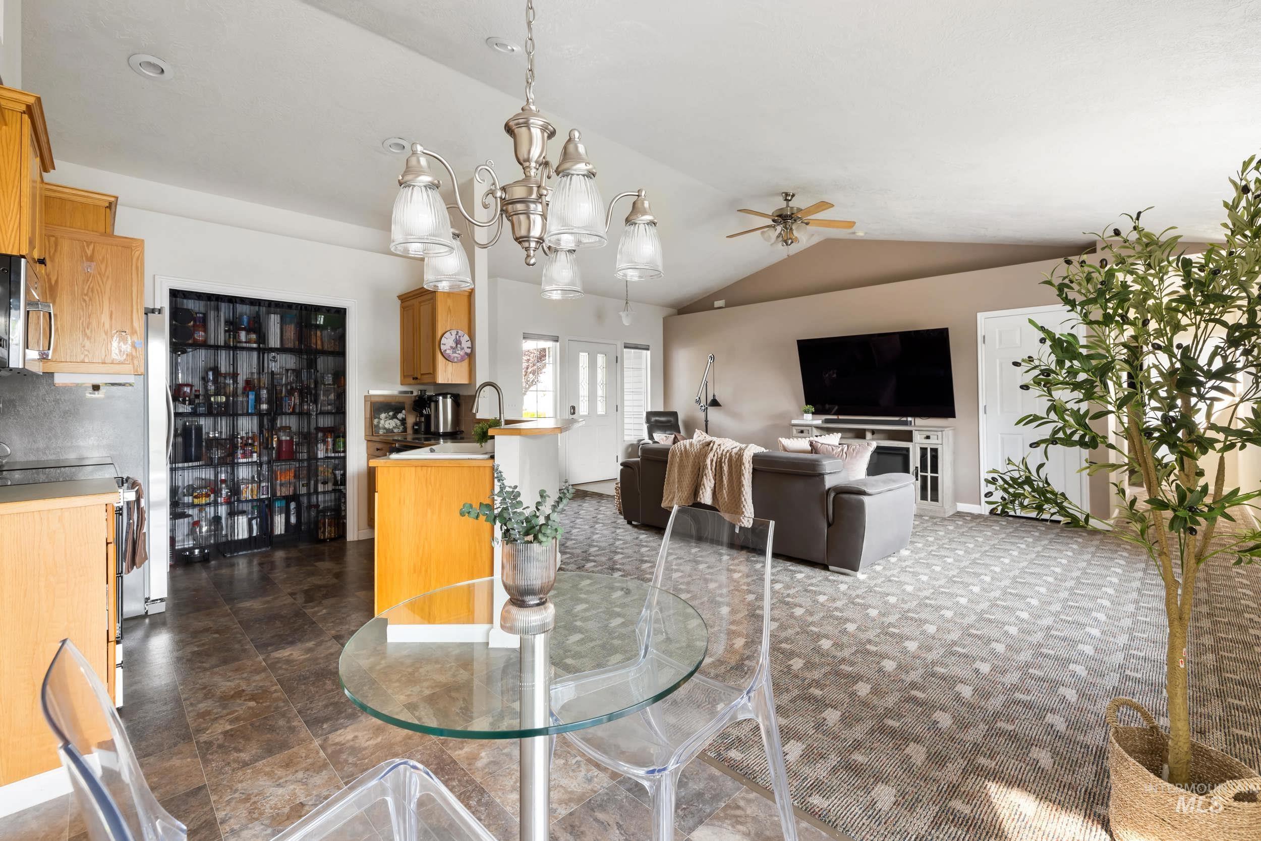 Dining space featuring a chandelier, vaulted ceiling, and ceiling fan