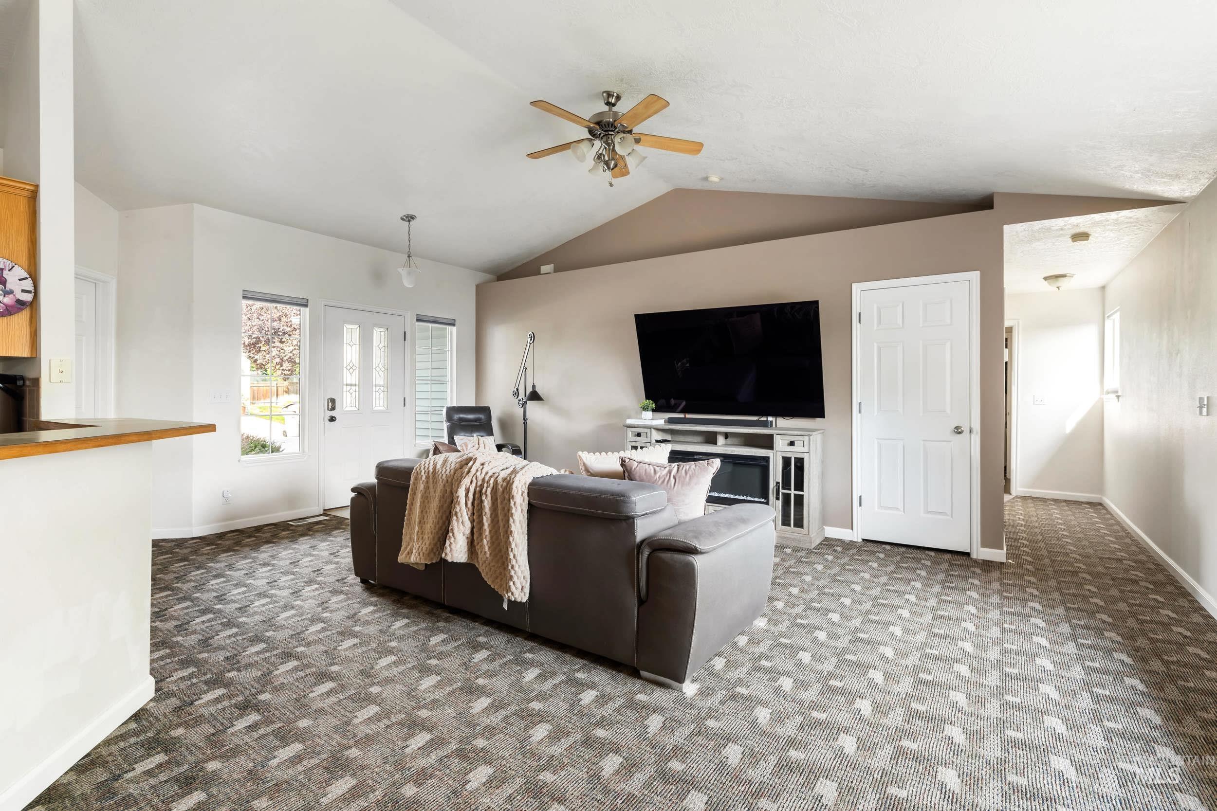 Living room with vaulted ceiling, carpet, and ceiling fan