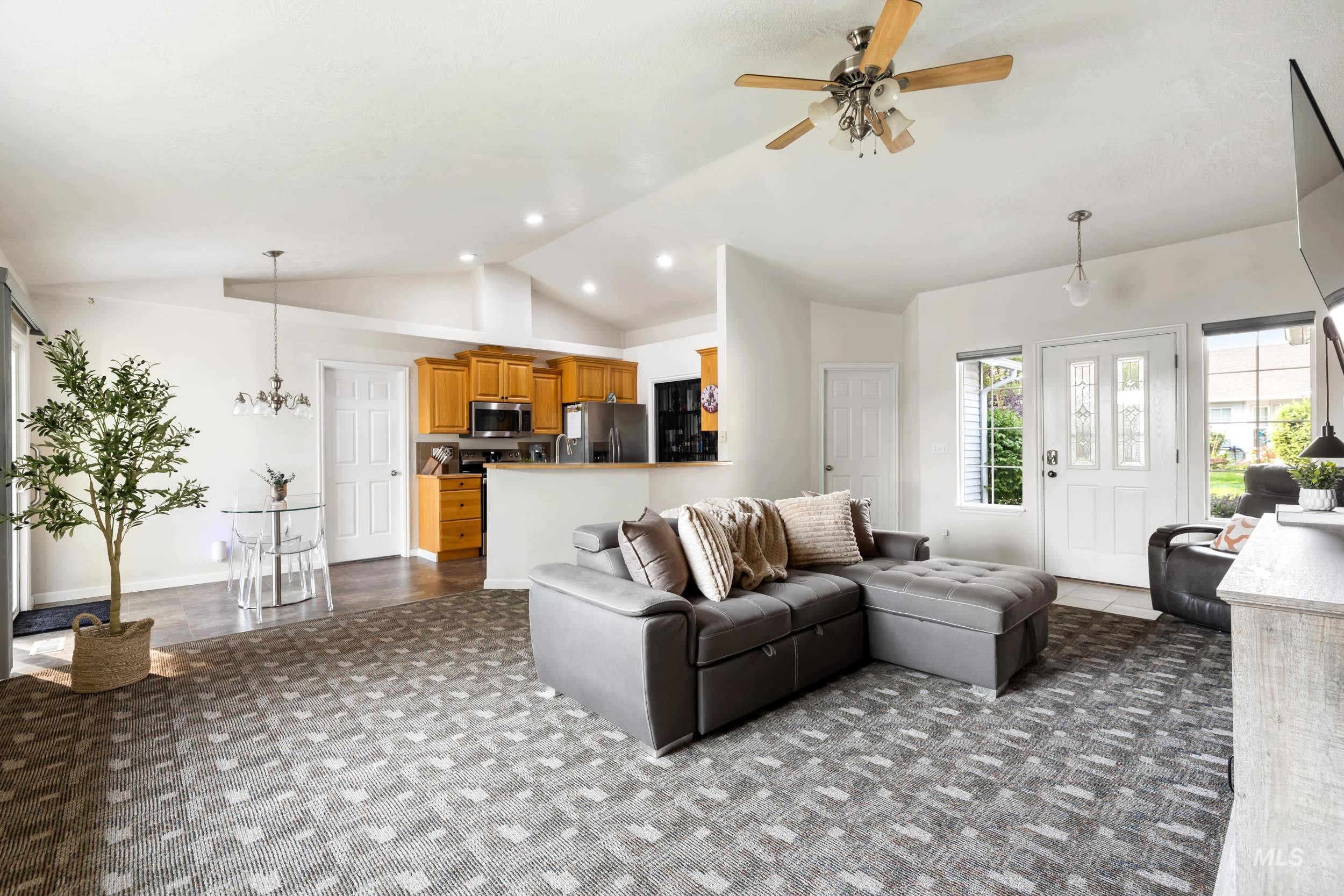 Living area featuring vaulted ceiling, ceiling fan, dark carpet, and recessed lighting