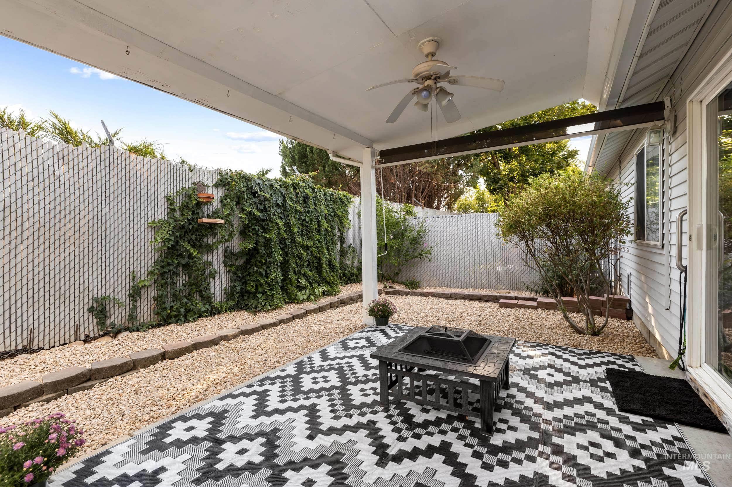 Fenced backyard with a patio, ceiling fan, and a fire pit