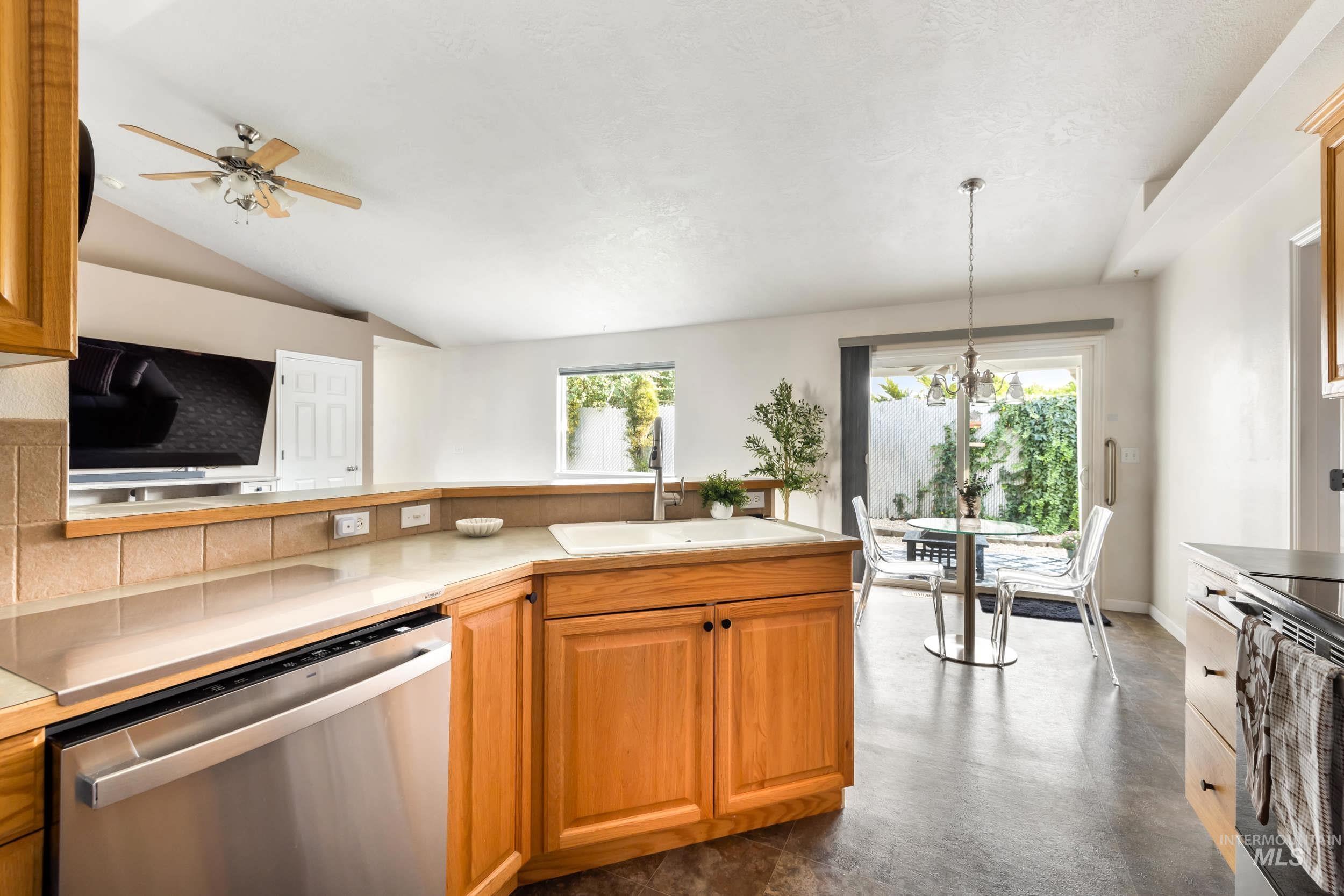 Kitchen featuring appliances with stainless steel finishes, light countertops, healthy amount of natural light, pendant lighting, and lofted ceiling