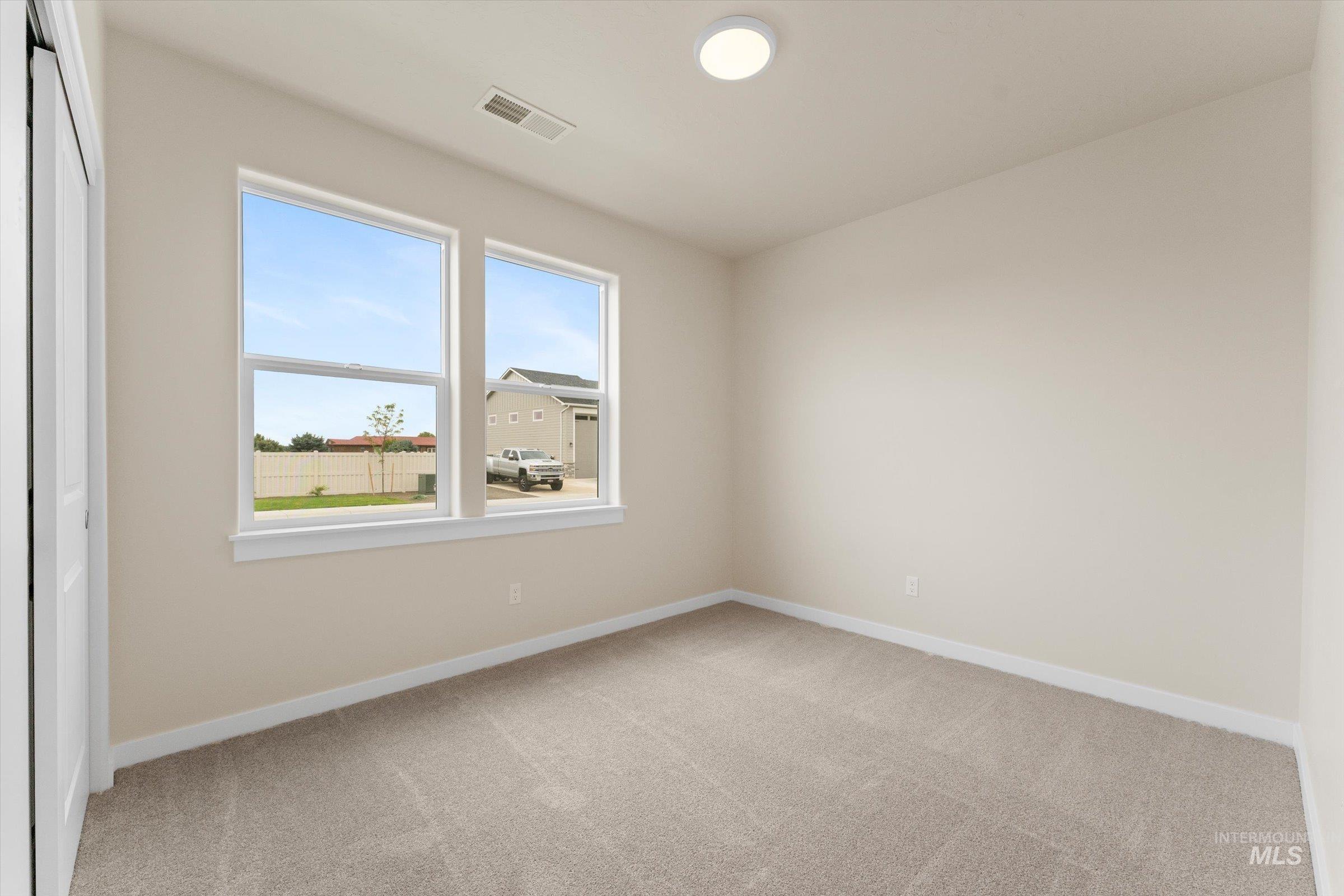 Spare room featuring light carpet and baseboards