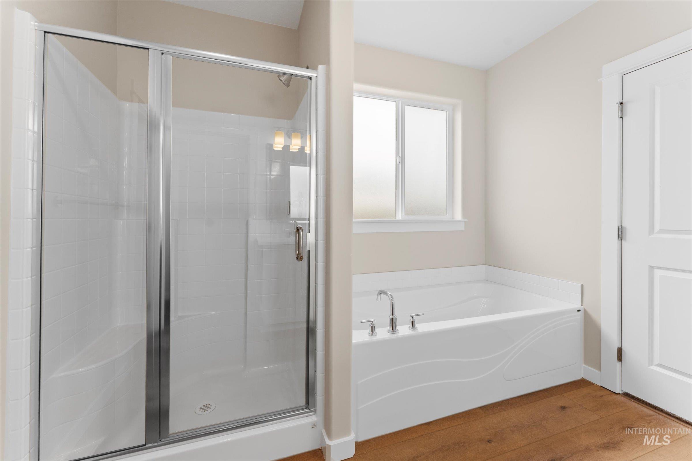 Full bathroom with wood finished floors, a stall shower, and a bath