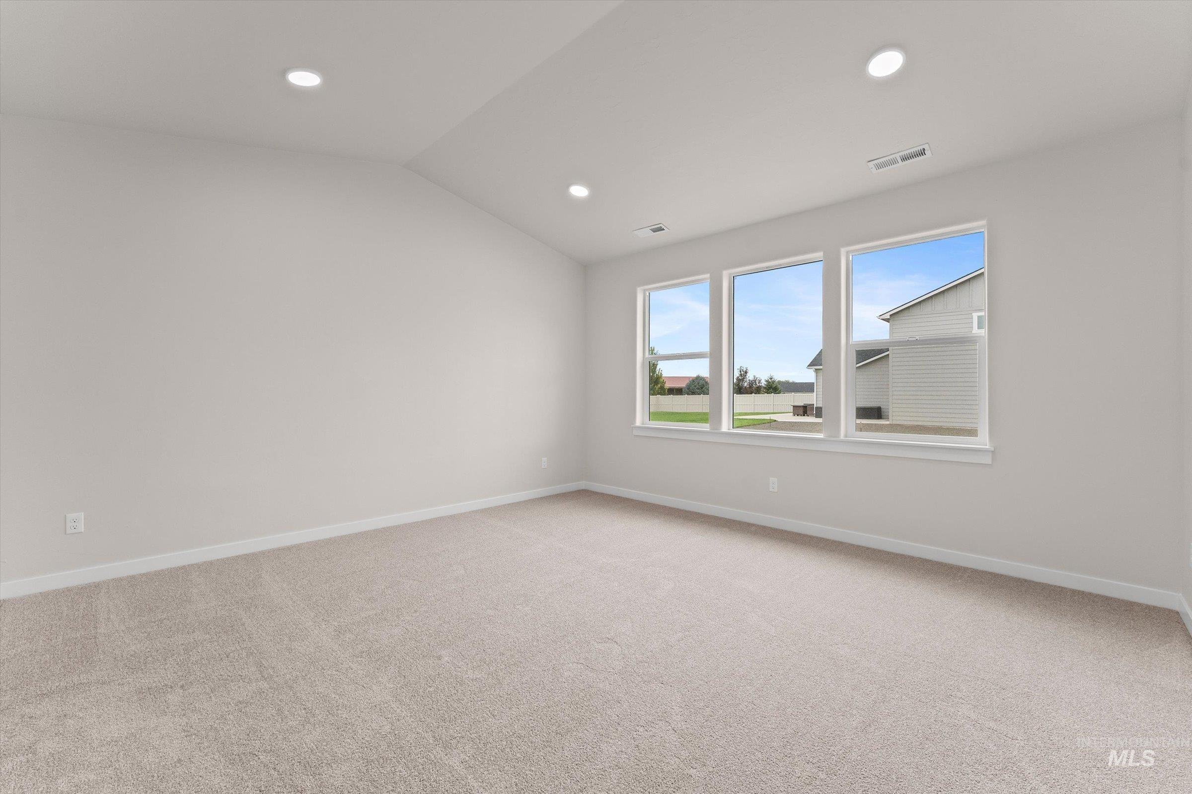 Empty room featuring light carpet, lofted ceiling, and recessed lighting