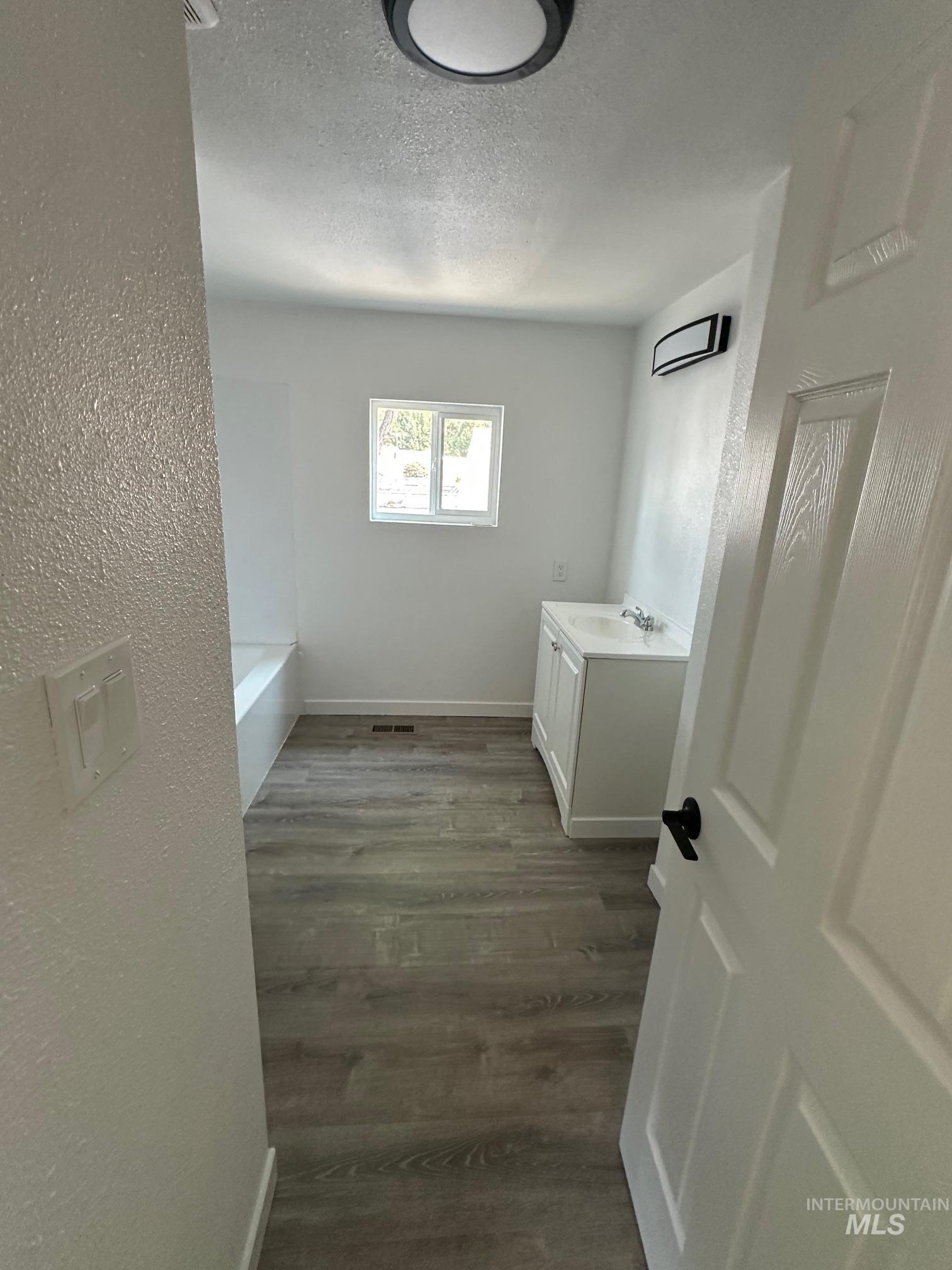 Laundry area with dark wood-style floors, a textured ceiling, and a textured wall