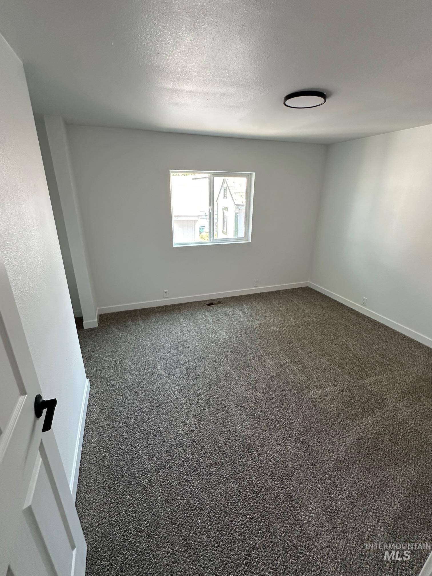 Carpeted empty room with baseboards and a textured ceiling