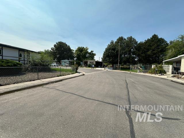 View of asphalt road featuring sidewalks and curbs