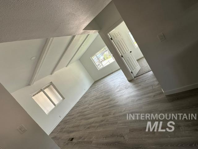 Bonus room with wood finished floors and a textured ceiling