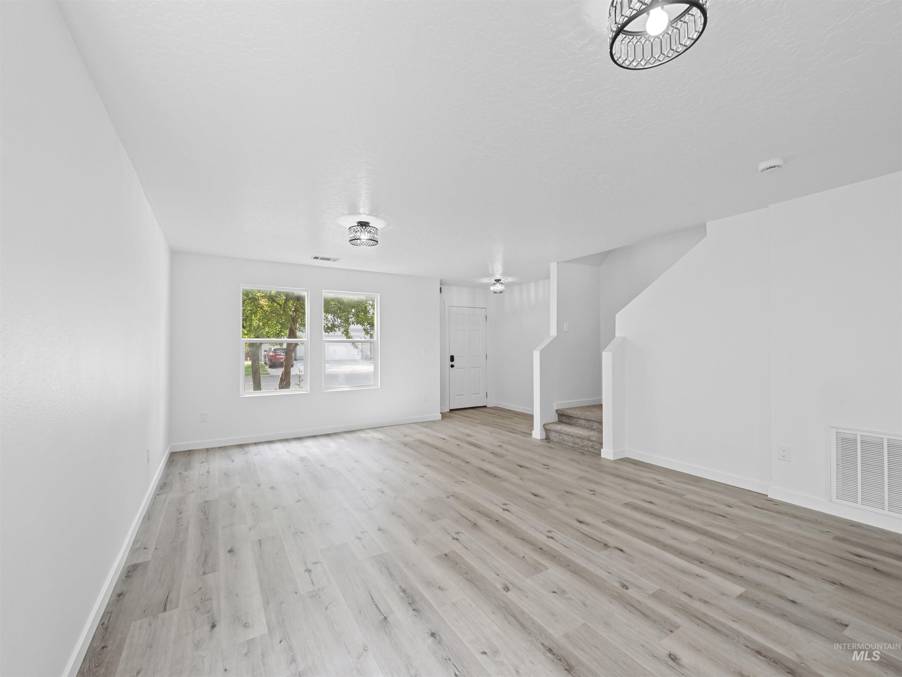 Unfurnished living room with stairs and light wood-type flooring