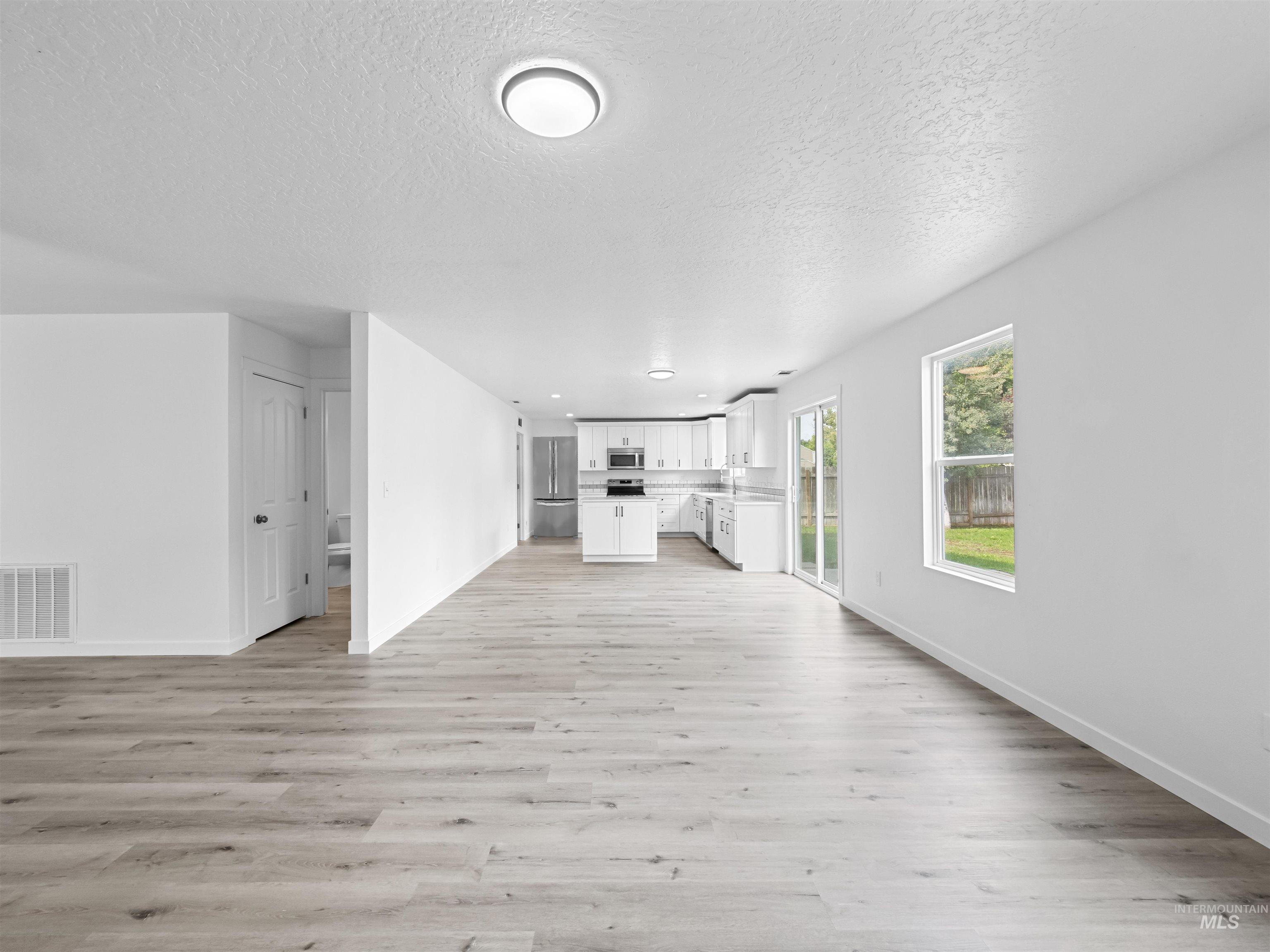 Unfurnished living room with light wood finished floors and a textured ceiling