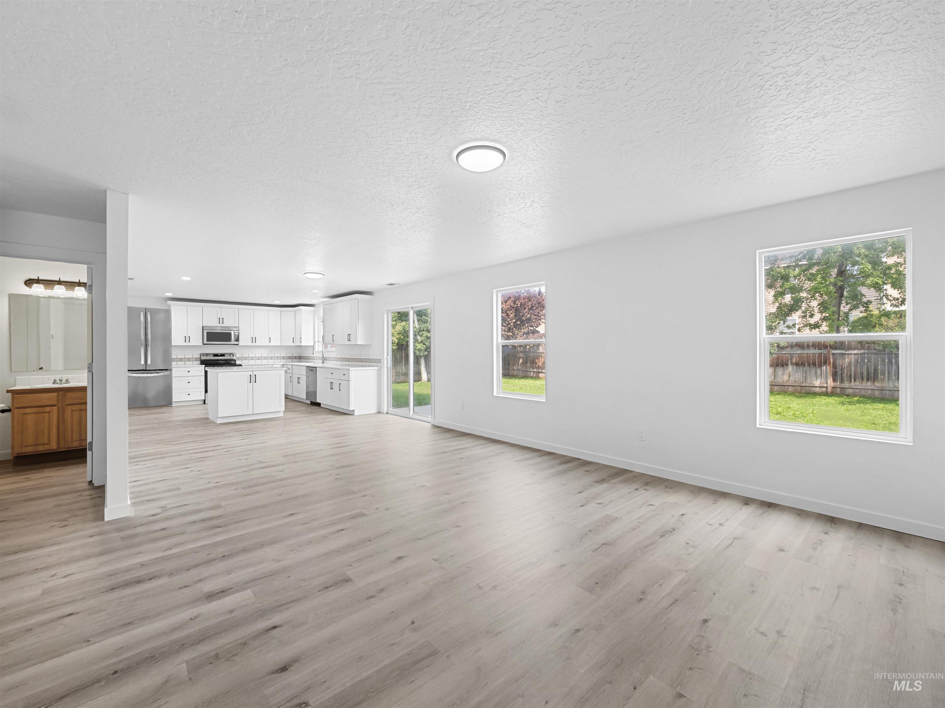 Unfurnished living room with light wood-type flooring, a textured ceiling, and a chandelier