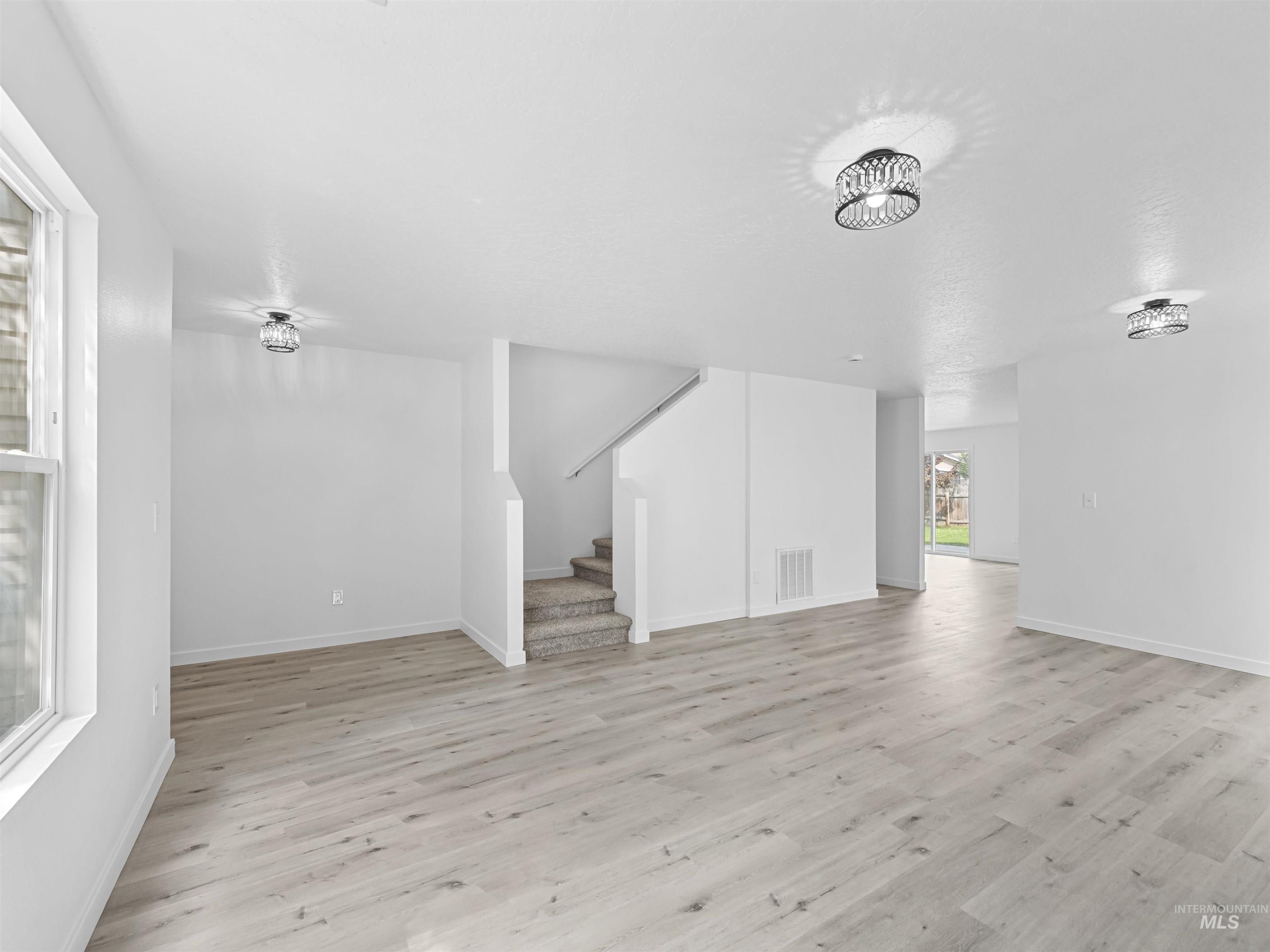 Additional living space featuring light wood finished floors and stairway