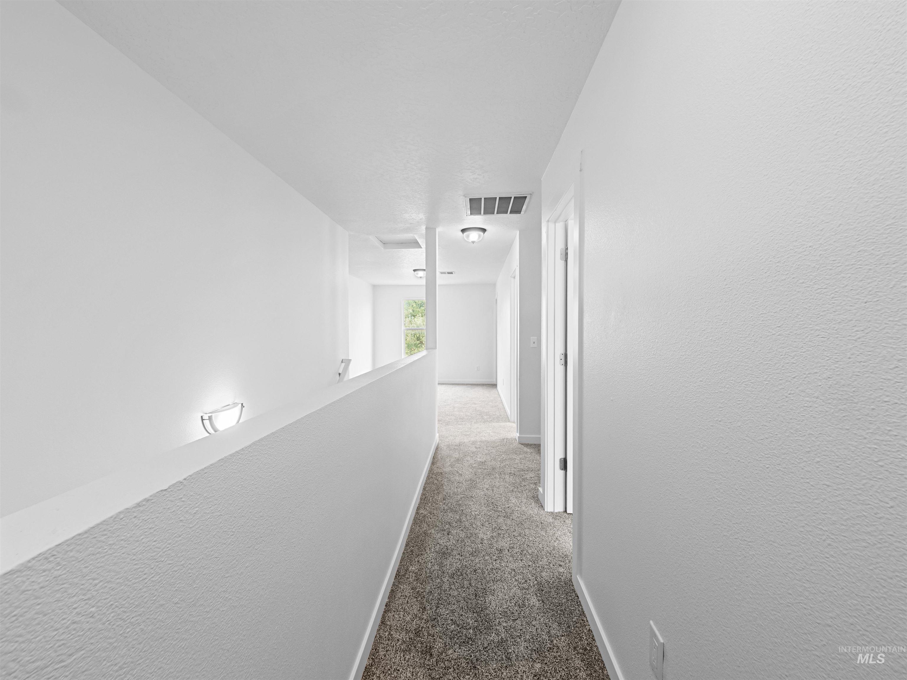 Corridor with dark carpet, an upstairs landing, and a textured wall