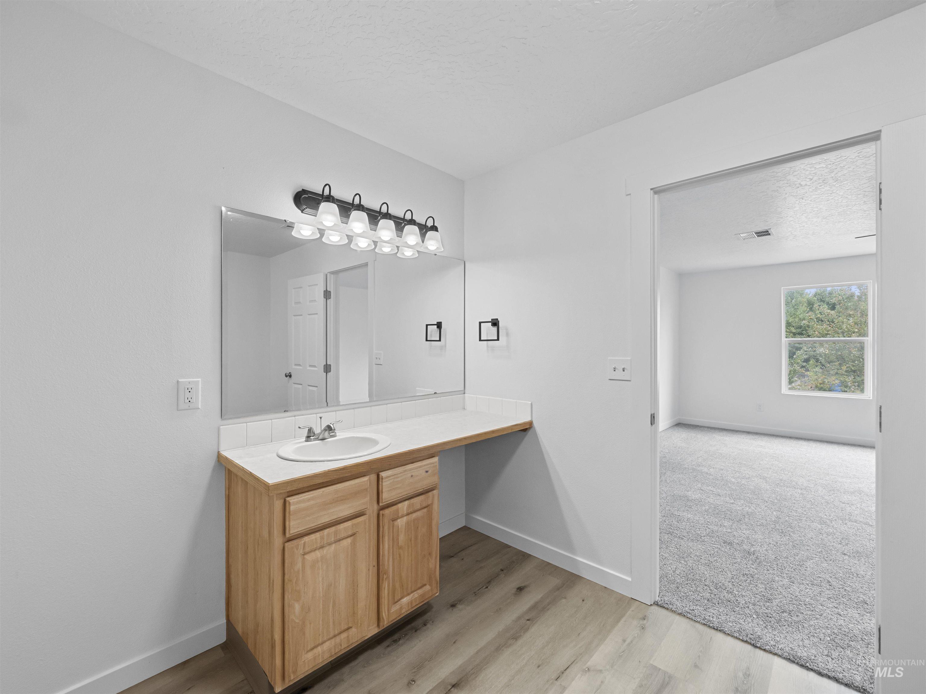 Bathroom featuring a textured ceiling, vanity, and light wood-style flooring