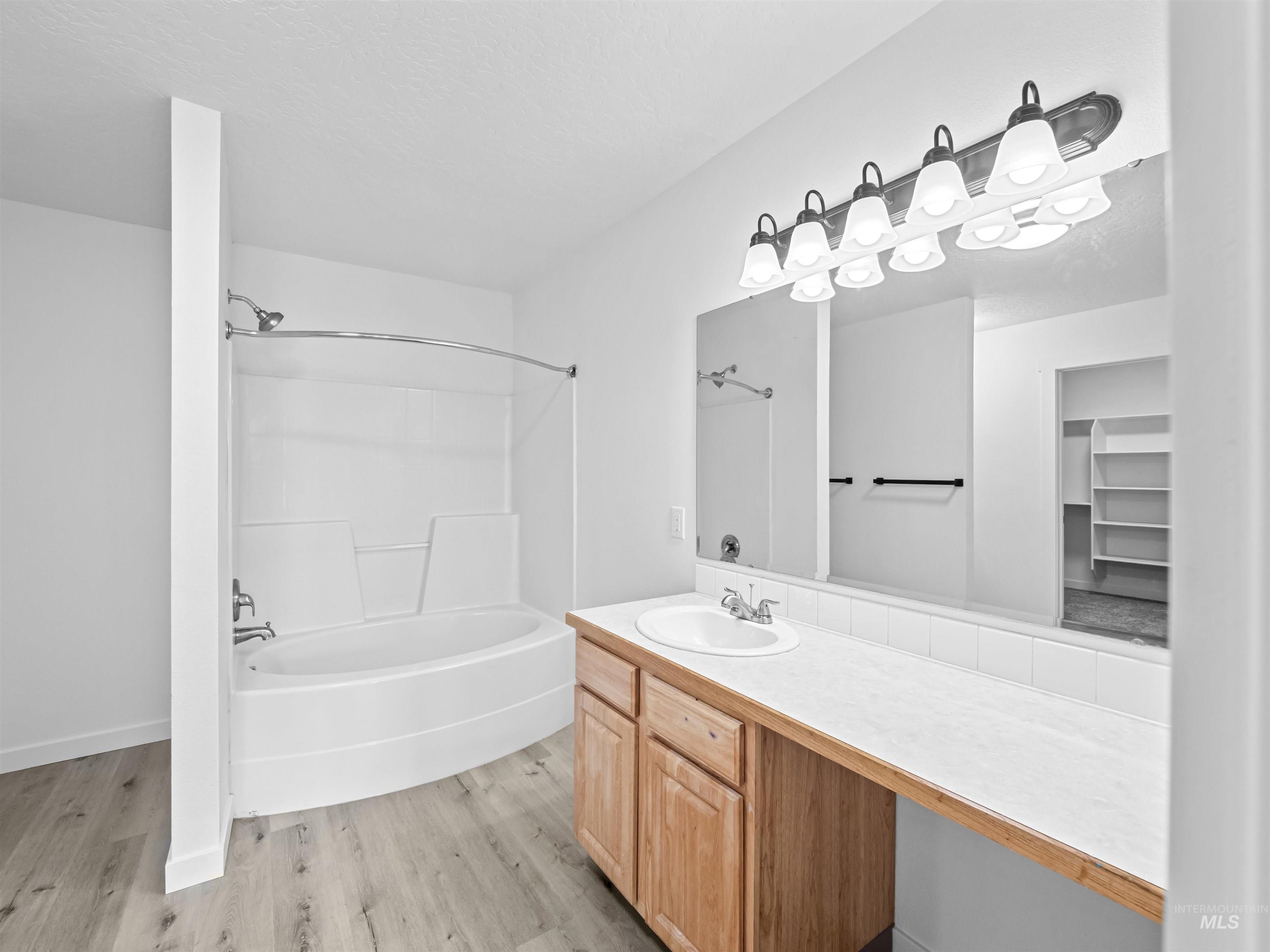 Bathroom with  shower combination, light wood-type flooring, vanity, and a textured ceiling