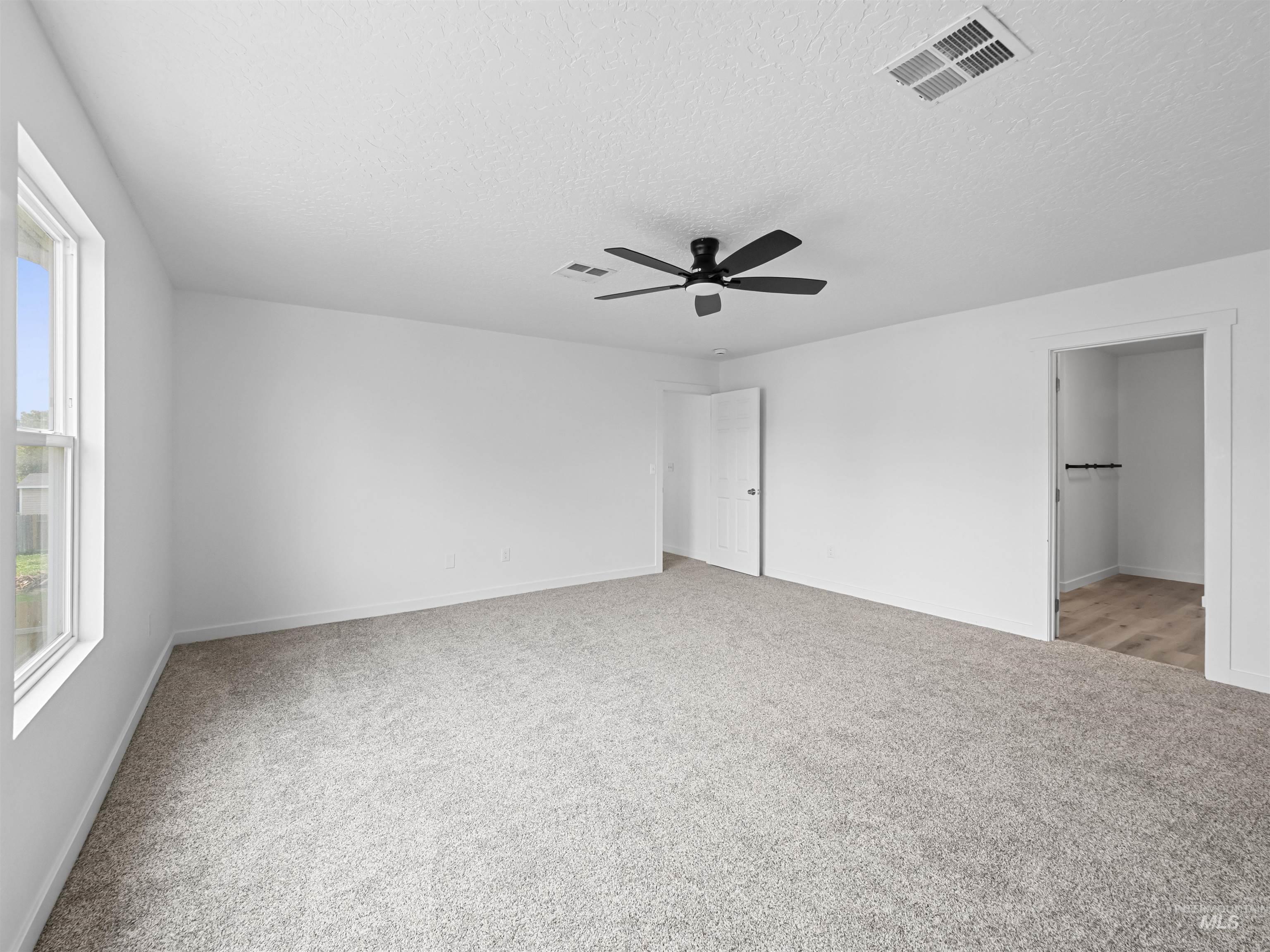 Unfurnished bedroom featuring light colored carpet, ceiling fan, and a textured ceiling