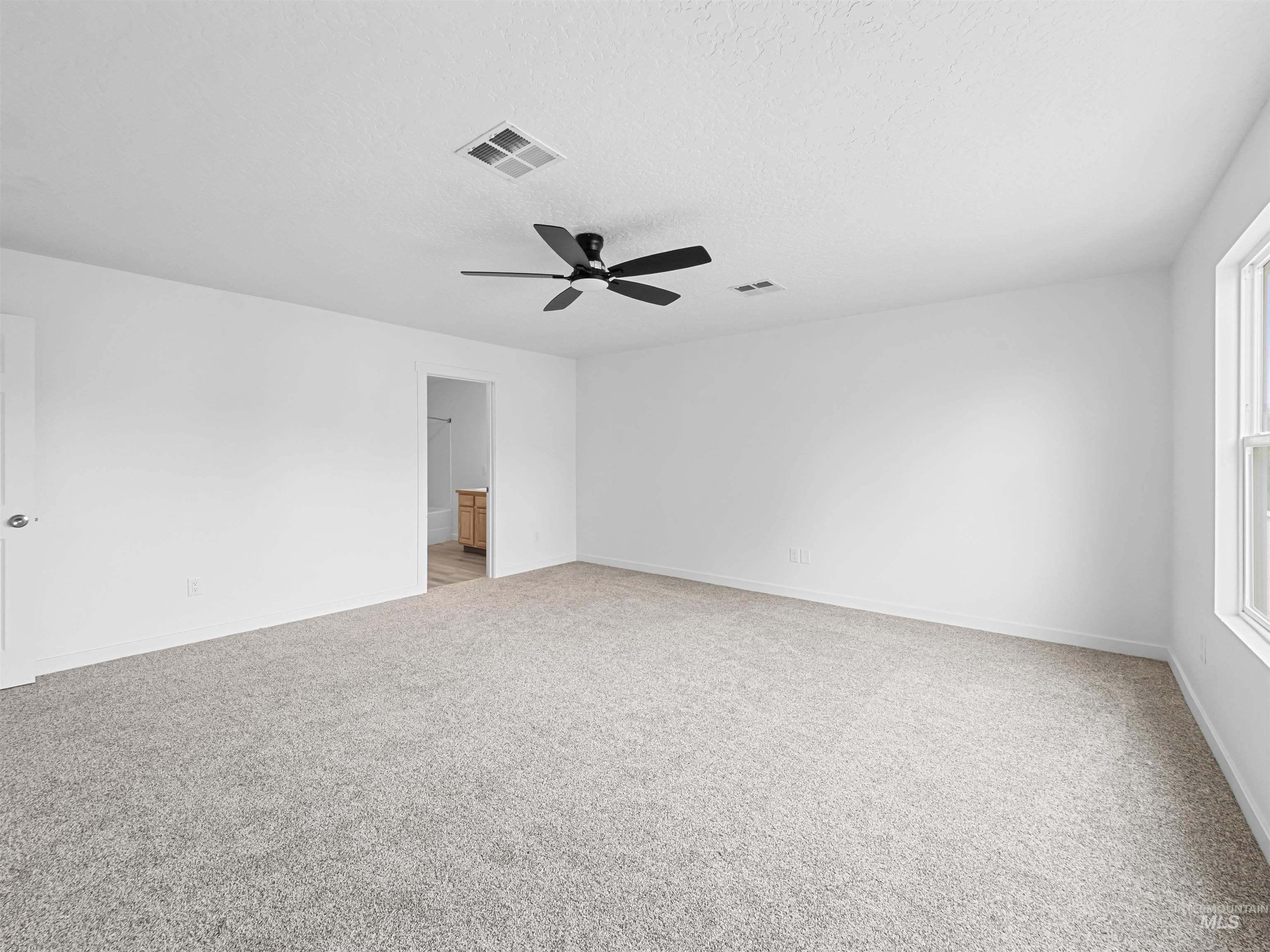 Empty room with light carpet and a textured ceiling