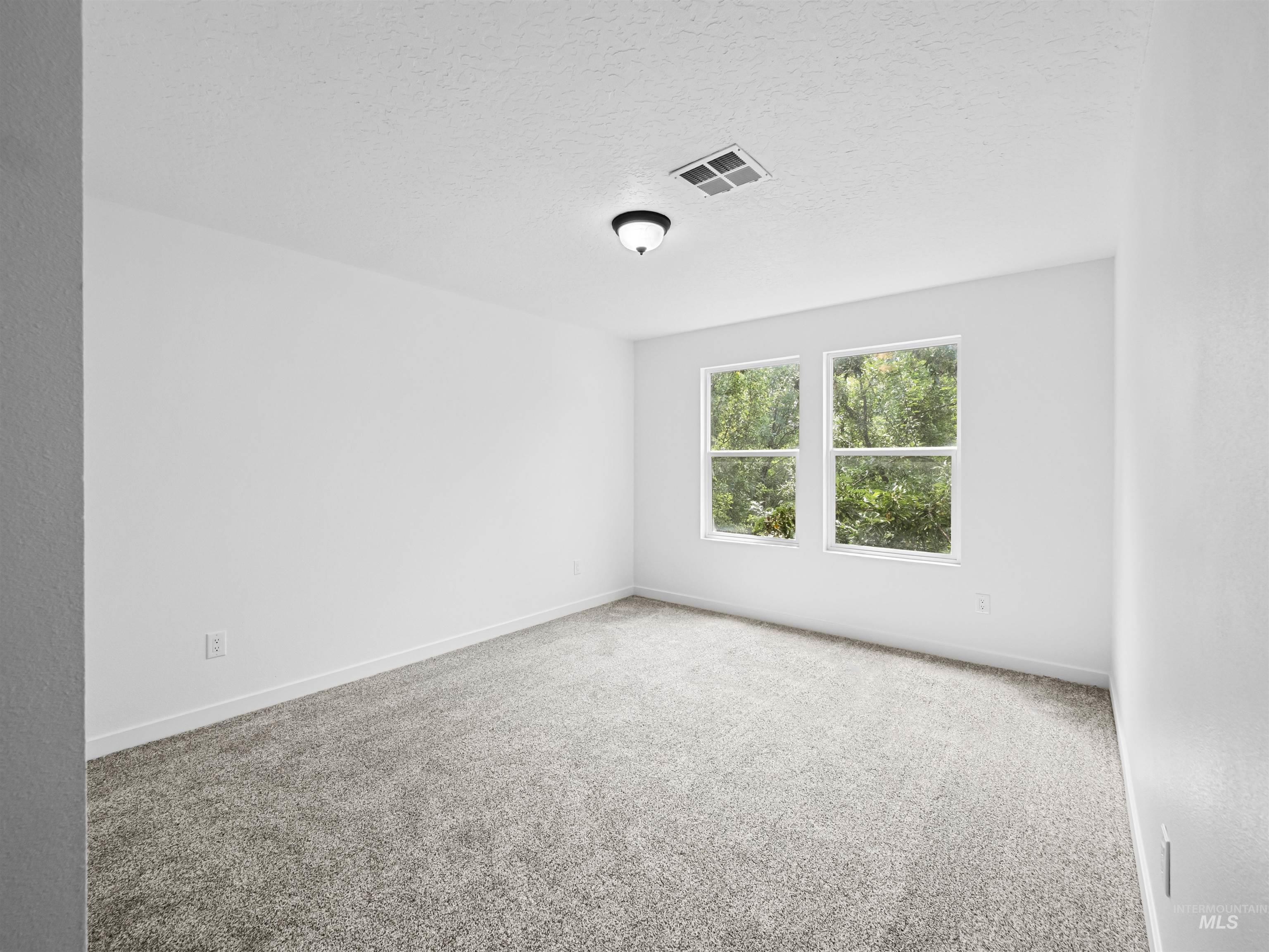 Carpeted empty room featuring a textured ceiling and baseboards