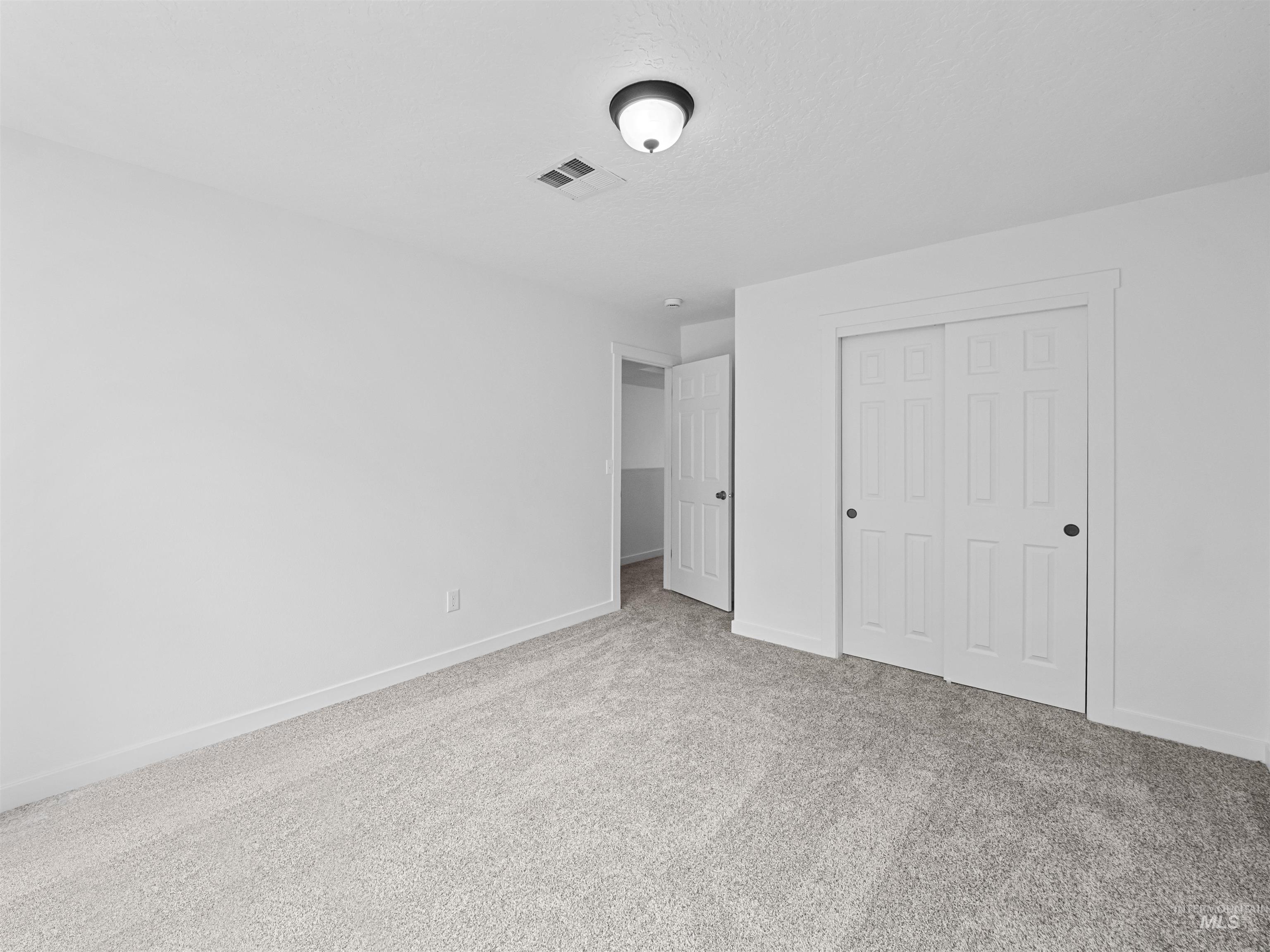 Unfurnished bedroom featuring light carpet and a closet