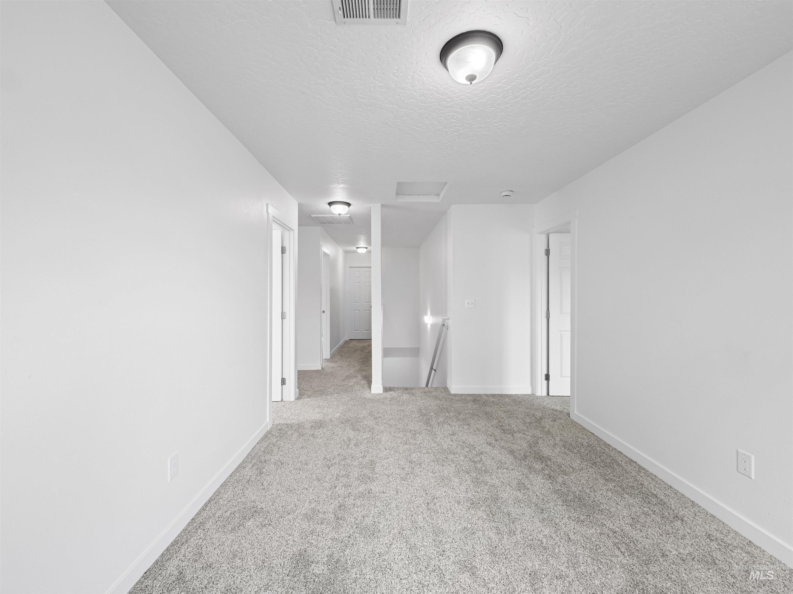 Spare room with light carpet, a textured ceiling, and attic access