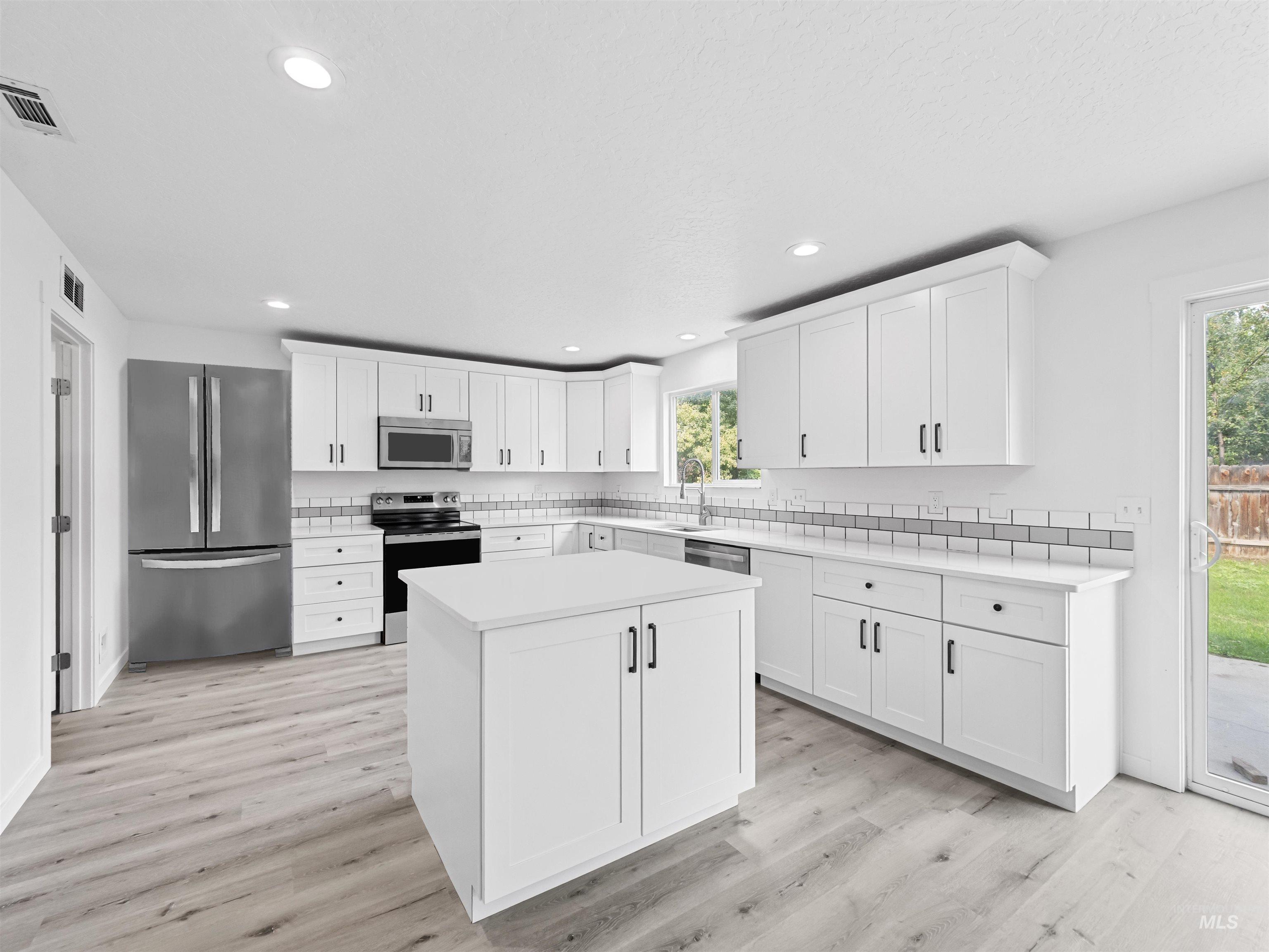 Kitchen featuring white cabinetry, appliances with stainless steel finishes, light countertops, light wood-style flooring, and recessed lighting