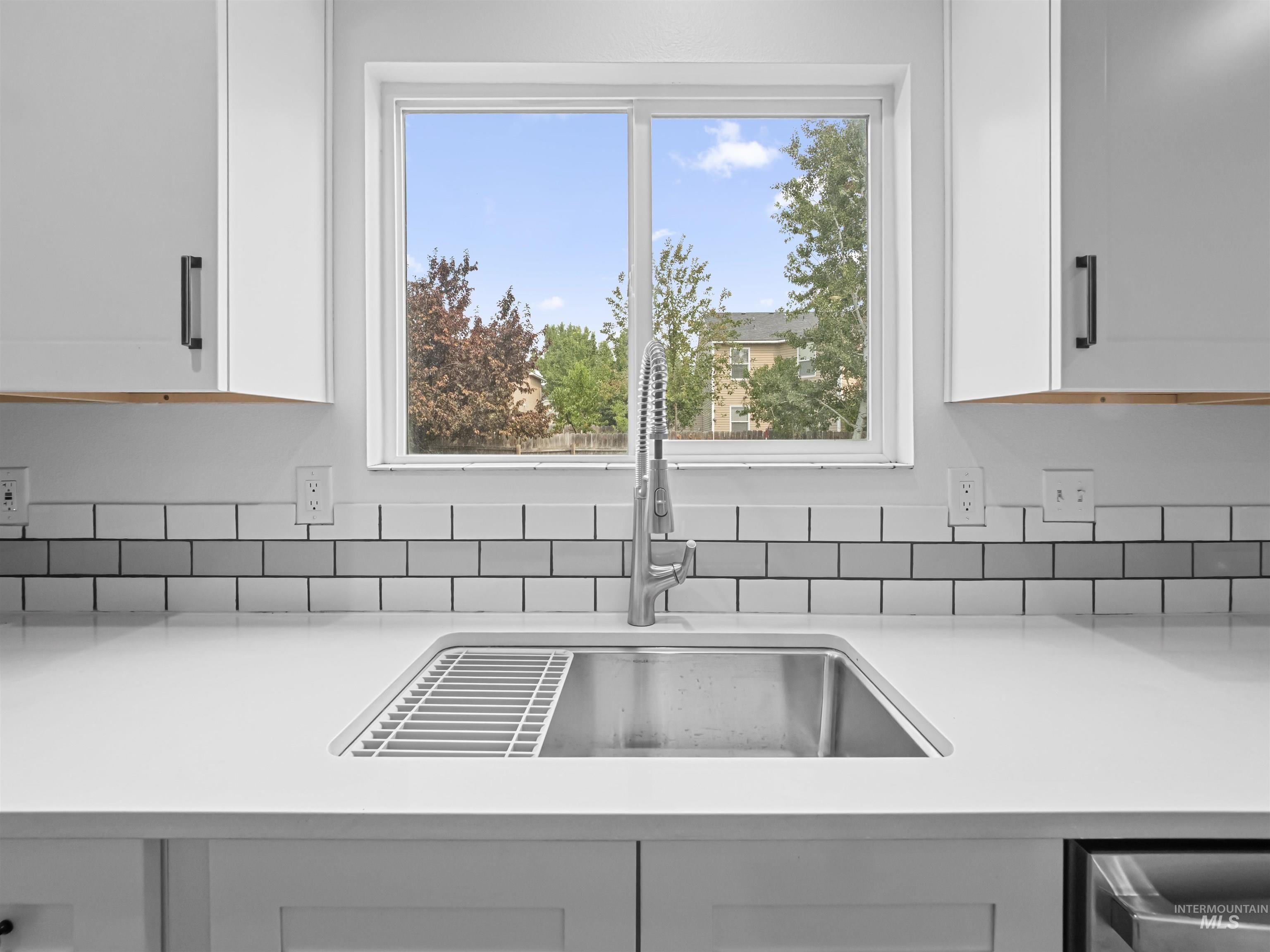 Kitchen view of white cabinets and light stone countertops