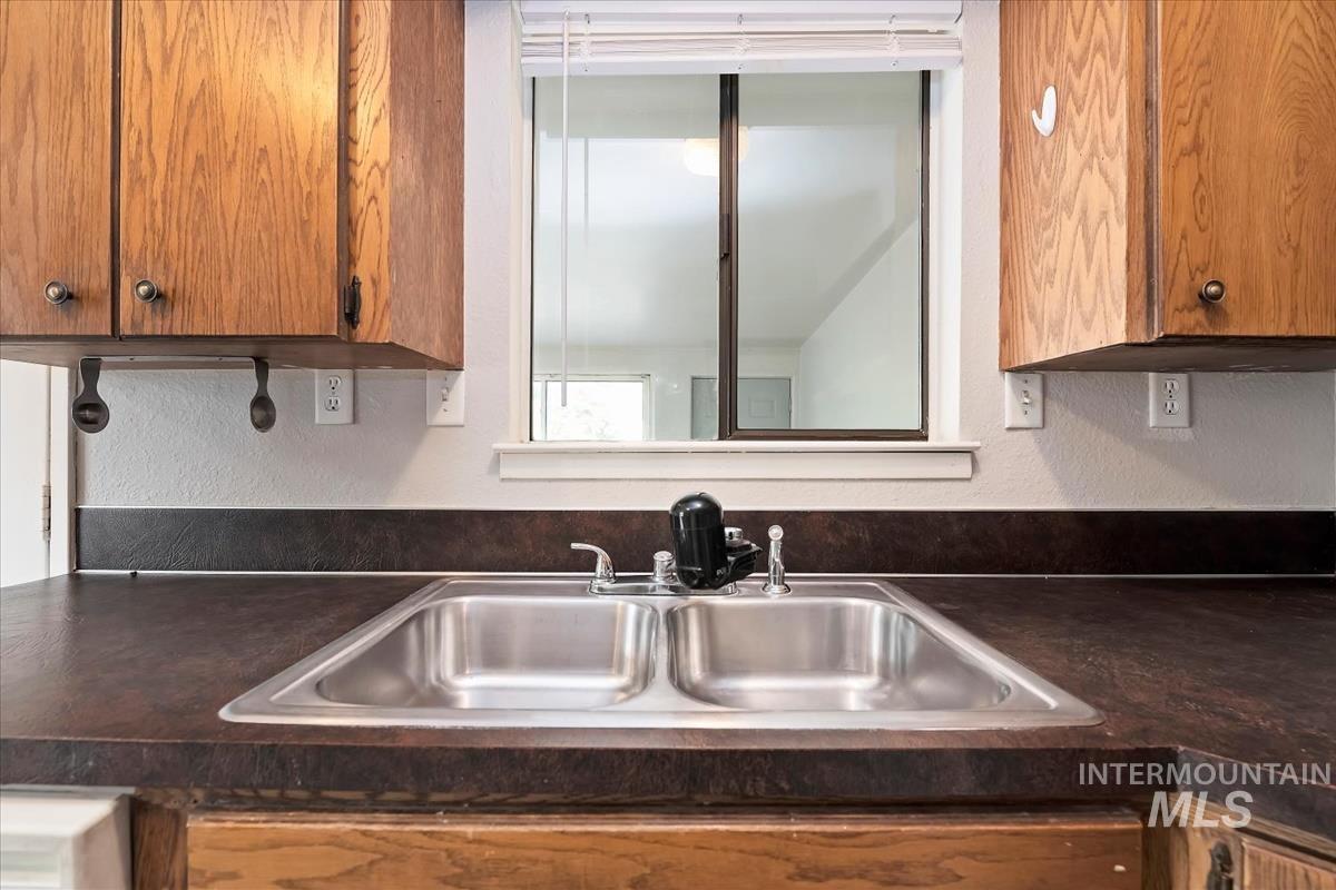 Kitchen with dark countertops, a textured wall, and brown cabinets