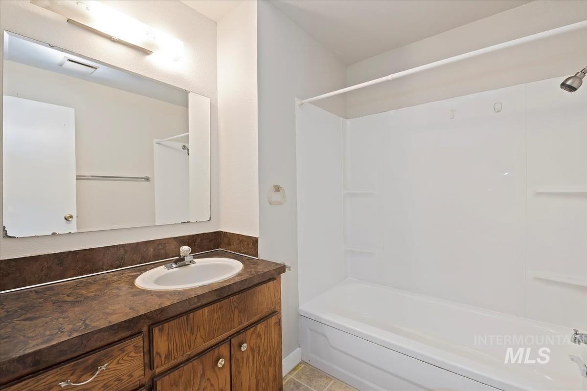 Bathroom with bathing tub / shower combination, vanity, and light tile patterned floors