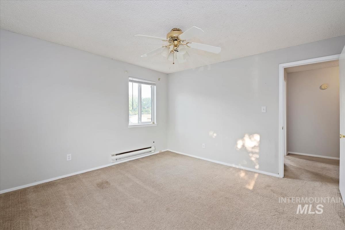 Spare room with carpet floors, a textured ceiling, a baseboard radiator, and ceiling fan