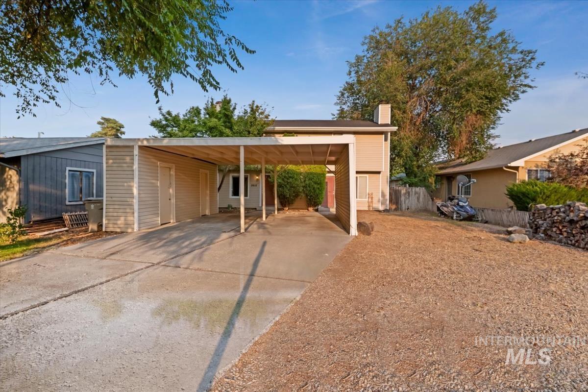 View of front of house featuring concrete driveway, a chimney, and an attached carport